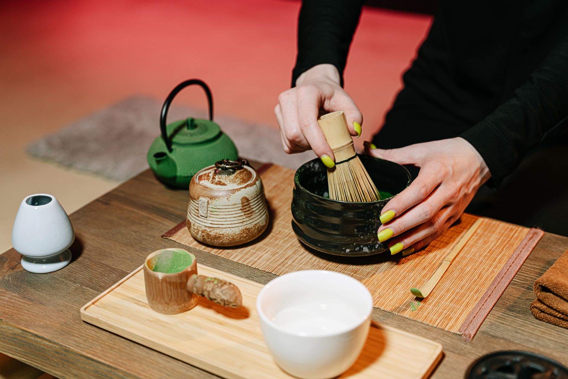 Ceramic tea cup filled with green tea on wooden tray beside water glass in traditional Japanese restaurant setting.