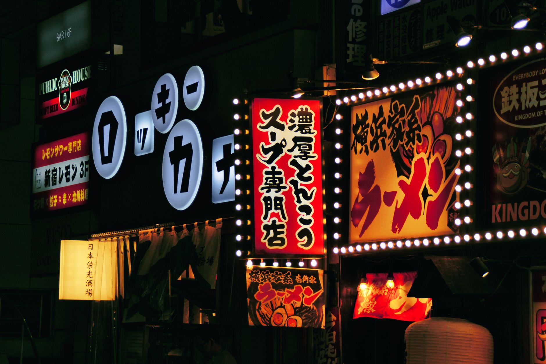 Narrow residential street in Tokyo with utility poles, vending machines, and small address number plates on building walls.