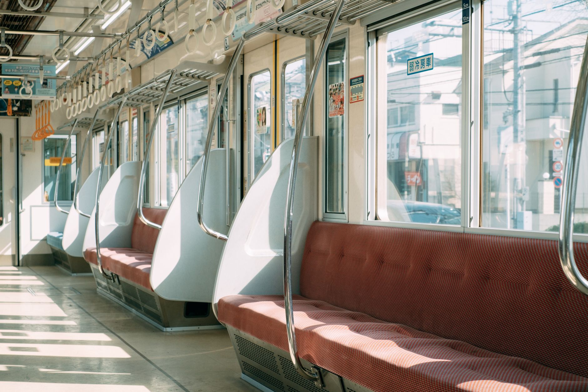 Elderly passenger seated in designated priority seat area marked with pink upholstery near Japanese train door.