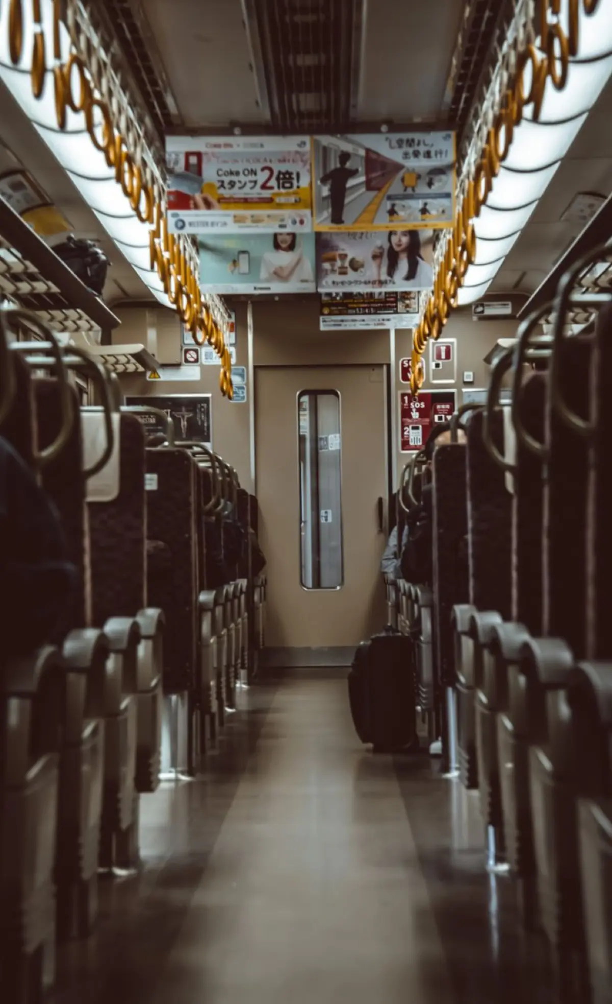 Elderly passenger seated in designated priority seat area marked with pink upholstery near Japanese train door.