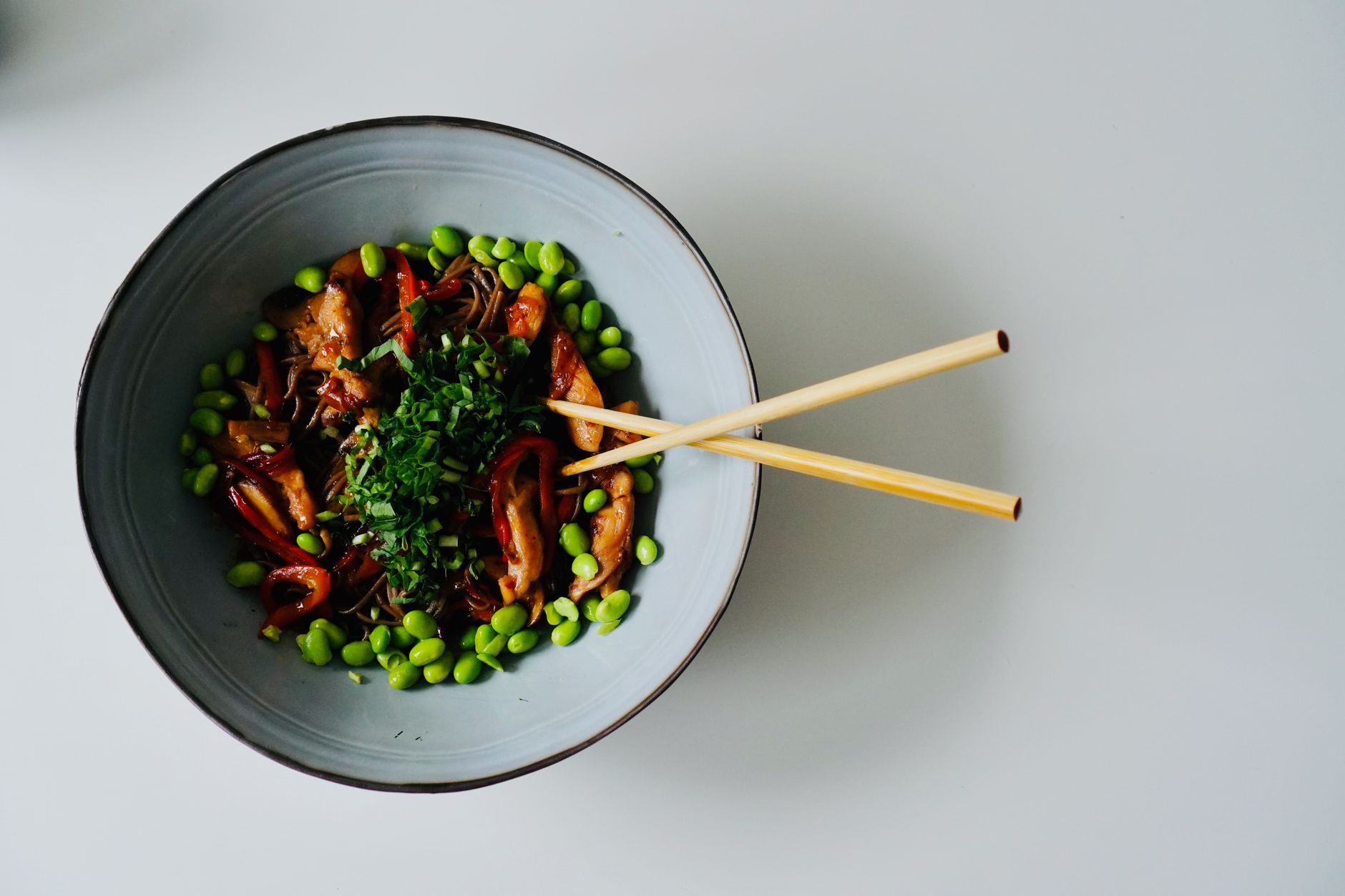 Steaming buckwheat soba noodles served in a traditional ceramic bowl with garnishes on a wooden table.