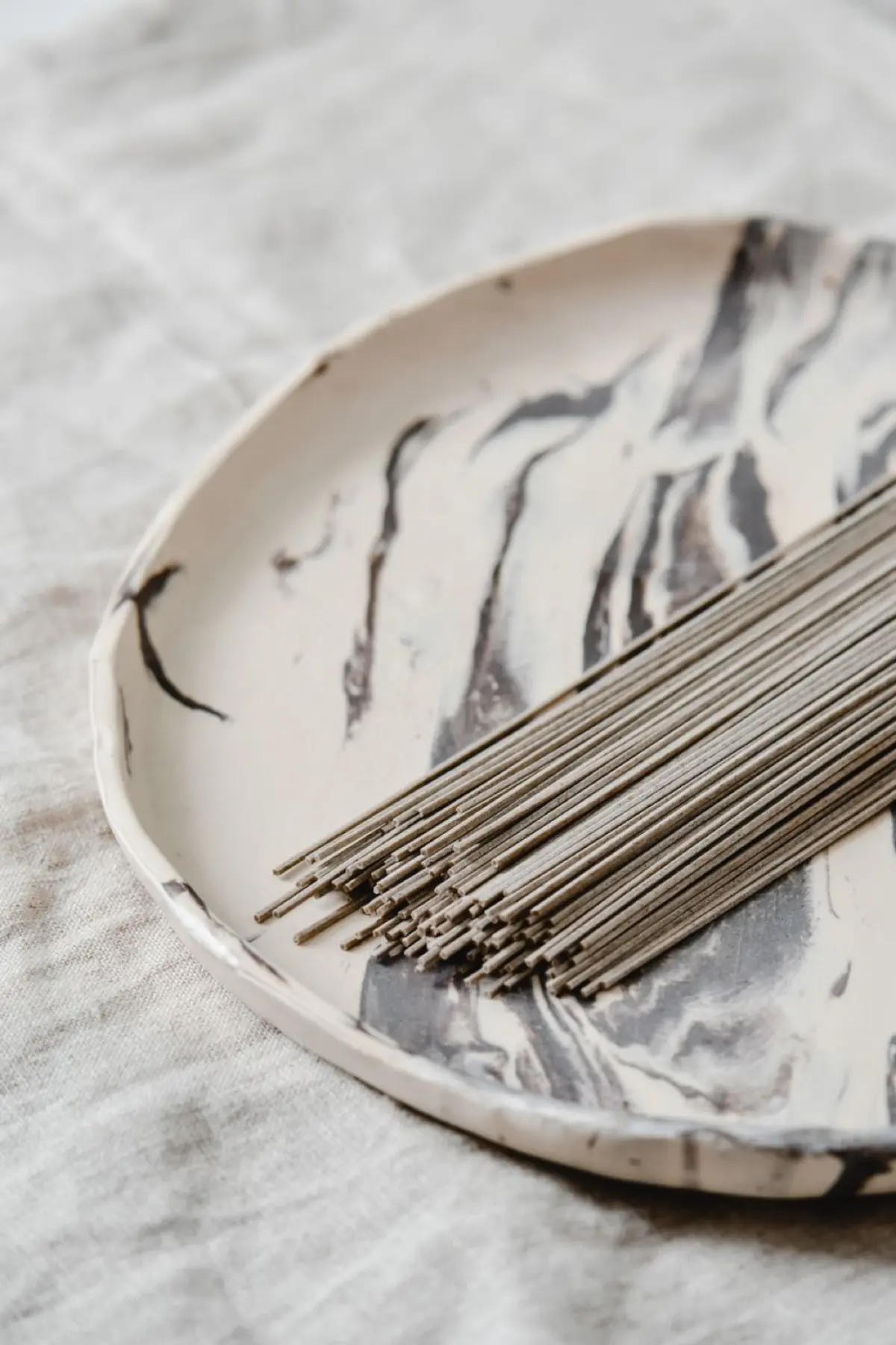 Steaming buckwheat soba noodles served in a traditional ceramic bowl with garnishes on a wooden table.