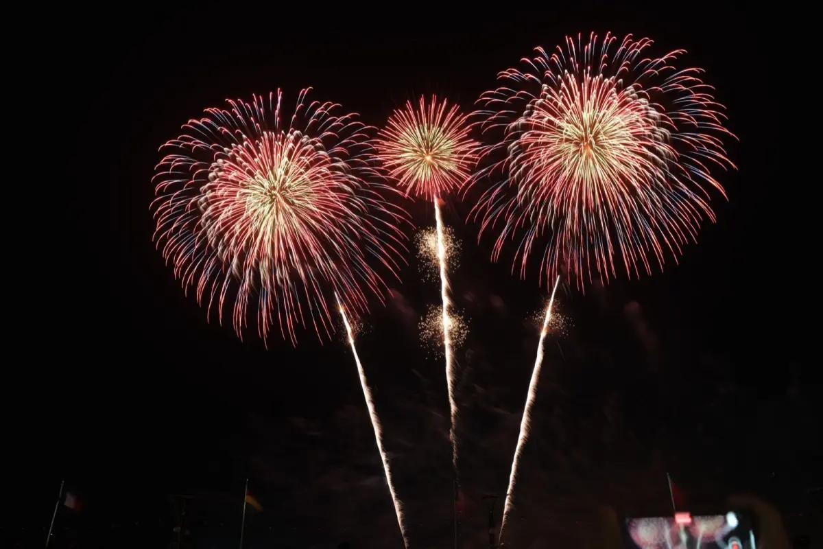 Large colourful fireworks bursting over a river crowded with spectators in yukata on a summer night in Japan