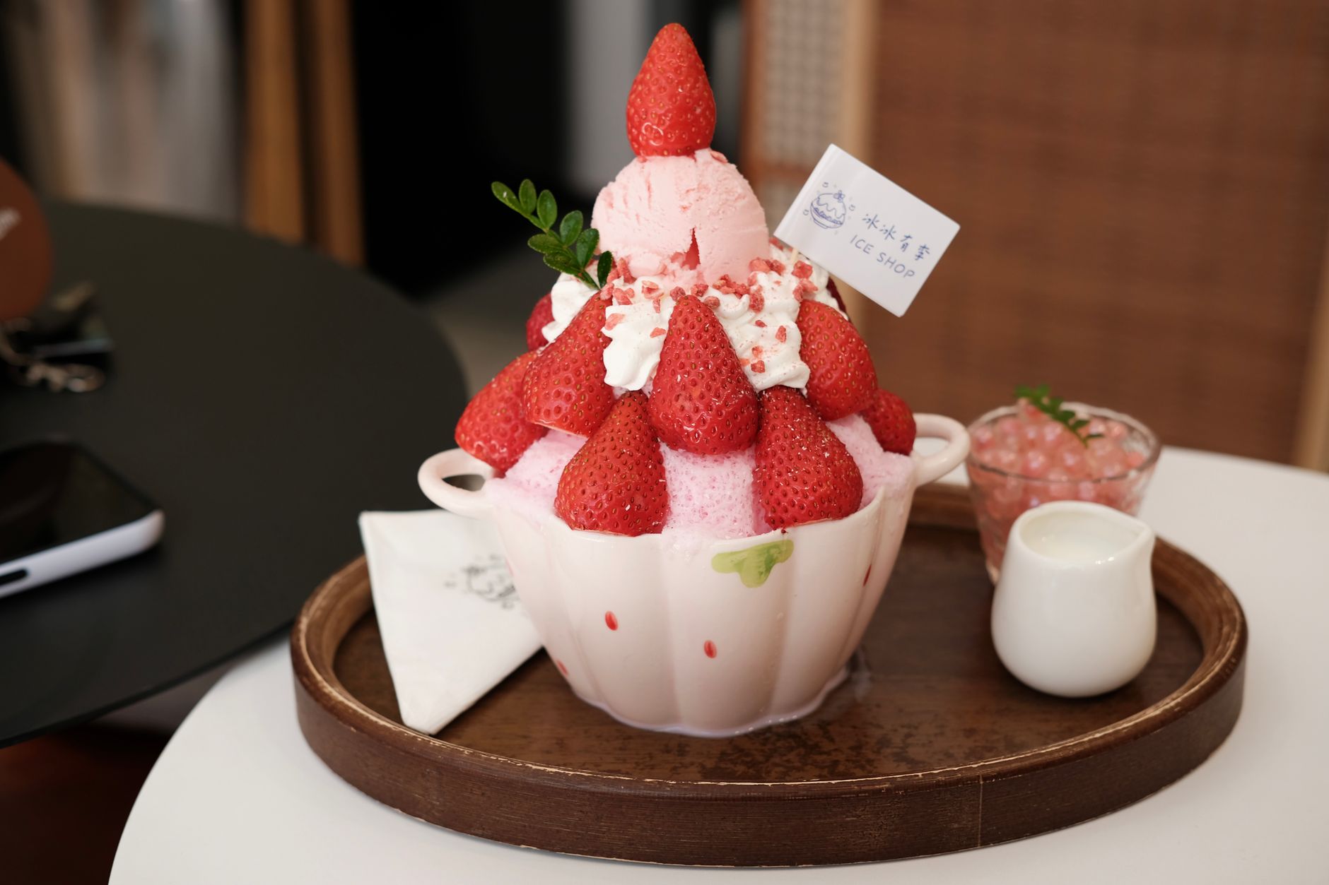 Bowl of colorful kakigori topped with sweet syrup and condensed milk, served on a wooden tray at a traditional Japanese summer festival.