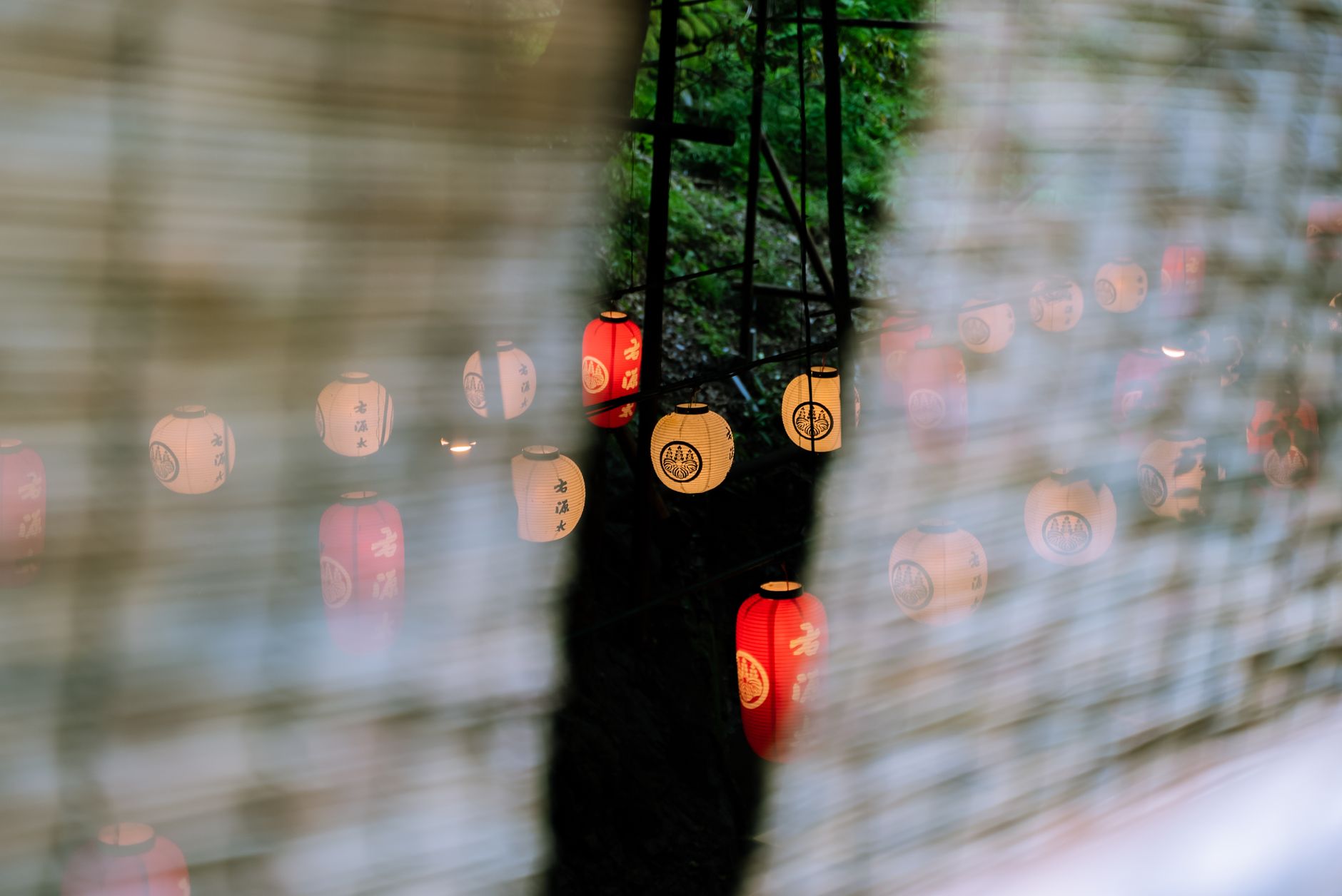 Illuminated paper lanterns floating on dark water at night during a traditional Japanese memorial ceremony.