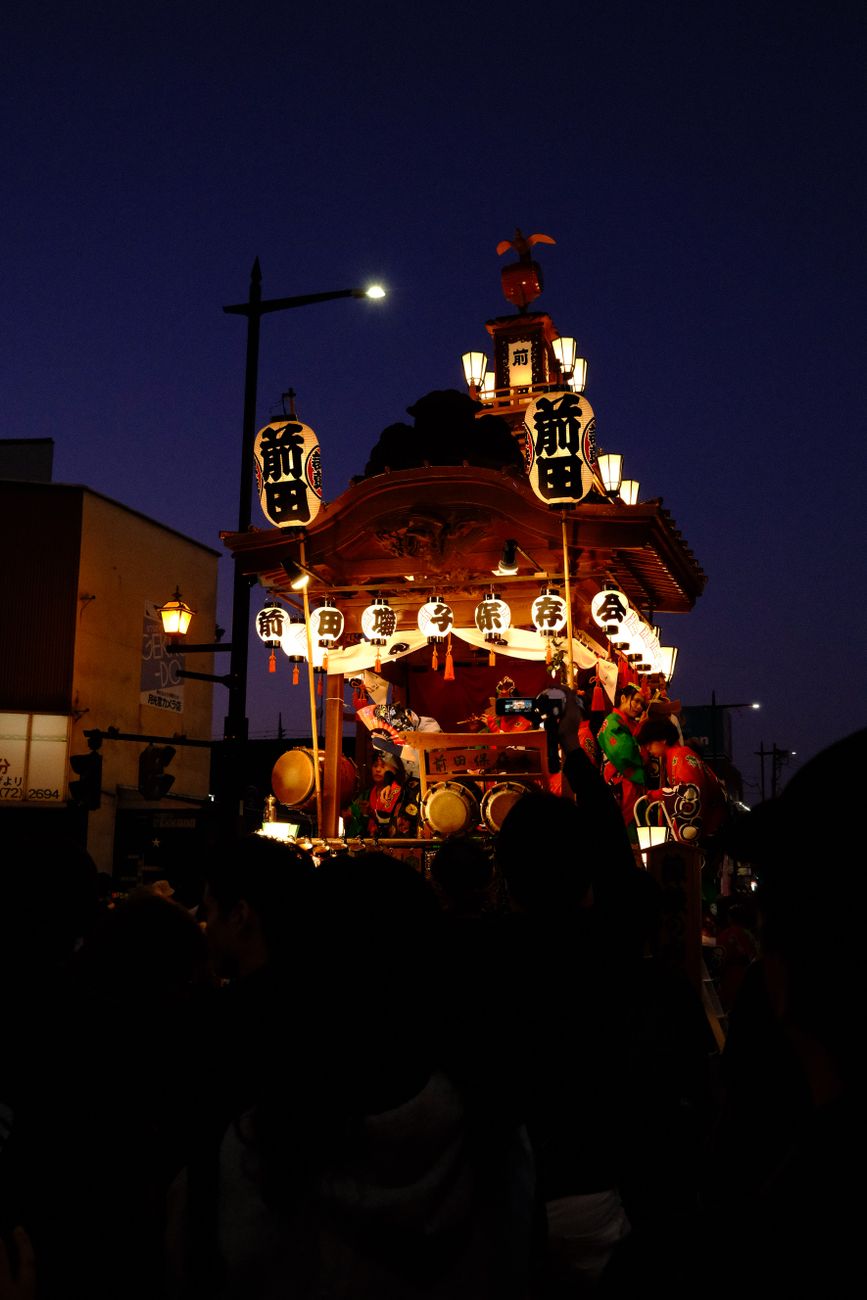 Illuminated paper lanterns floating on dark water at night during a traditional Japanese memorial ceremony.