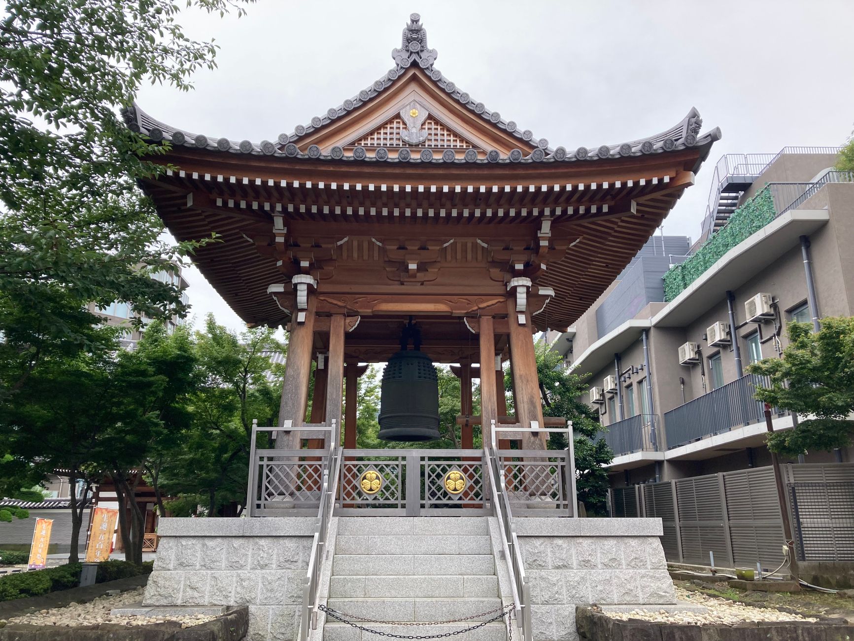 Large bronze temple bell hanging from wooden frame with thick rope, ready to be struck during Japanese New Year ceremony.
