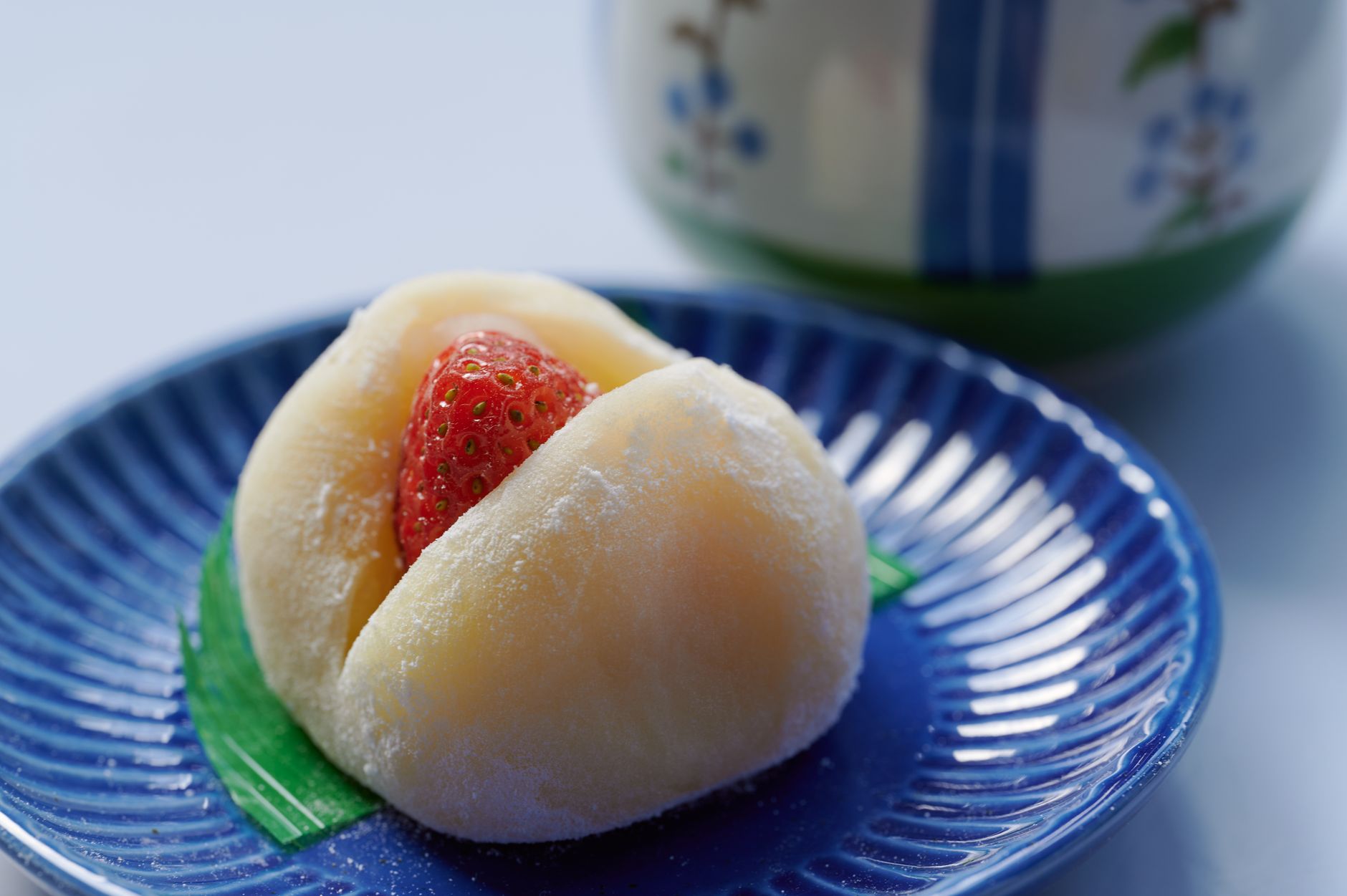 Round white mochi rice cakes stacked on red lacquer plates with pine decorations for Japanese New Year celebration.