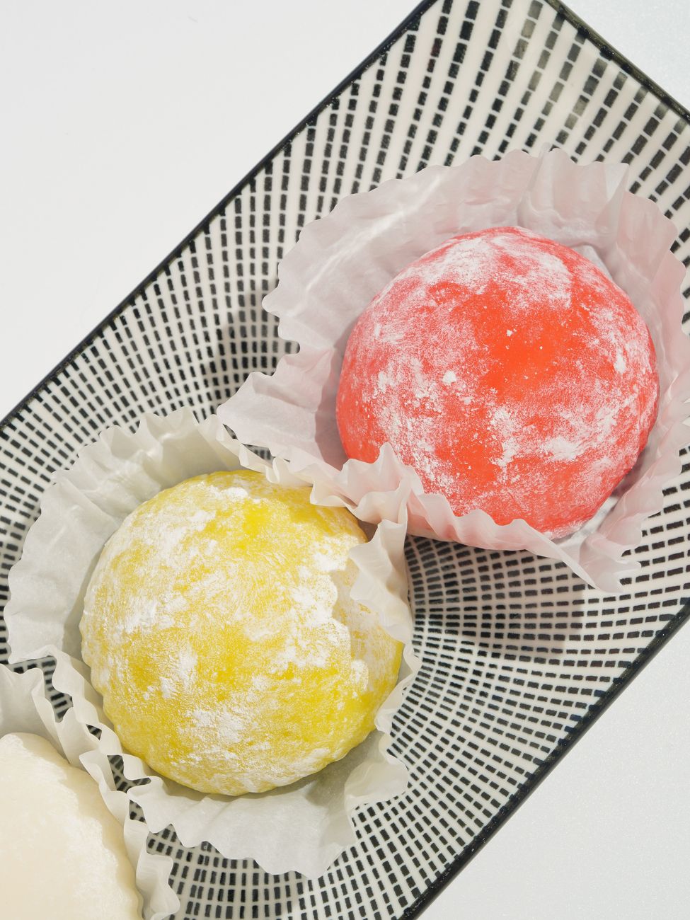 Round white mochi rice cakes stacked on red lacquer plates with pine decorations for Japanese New Year celebration.