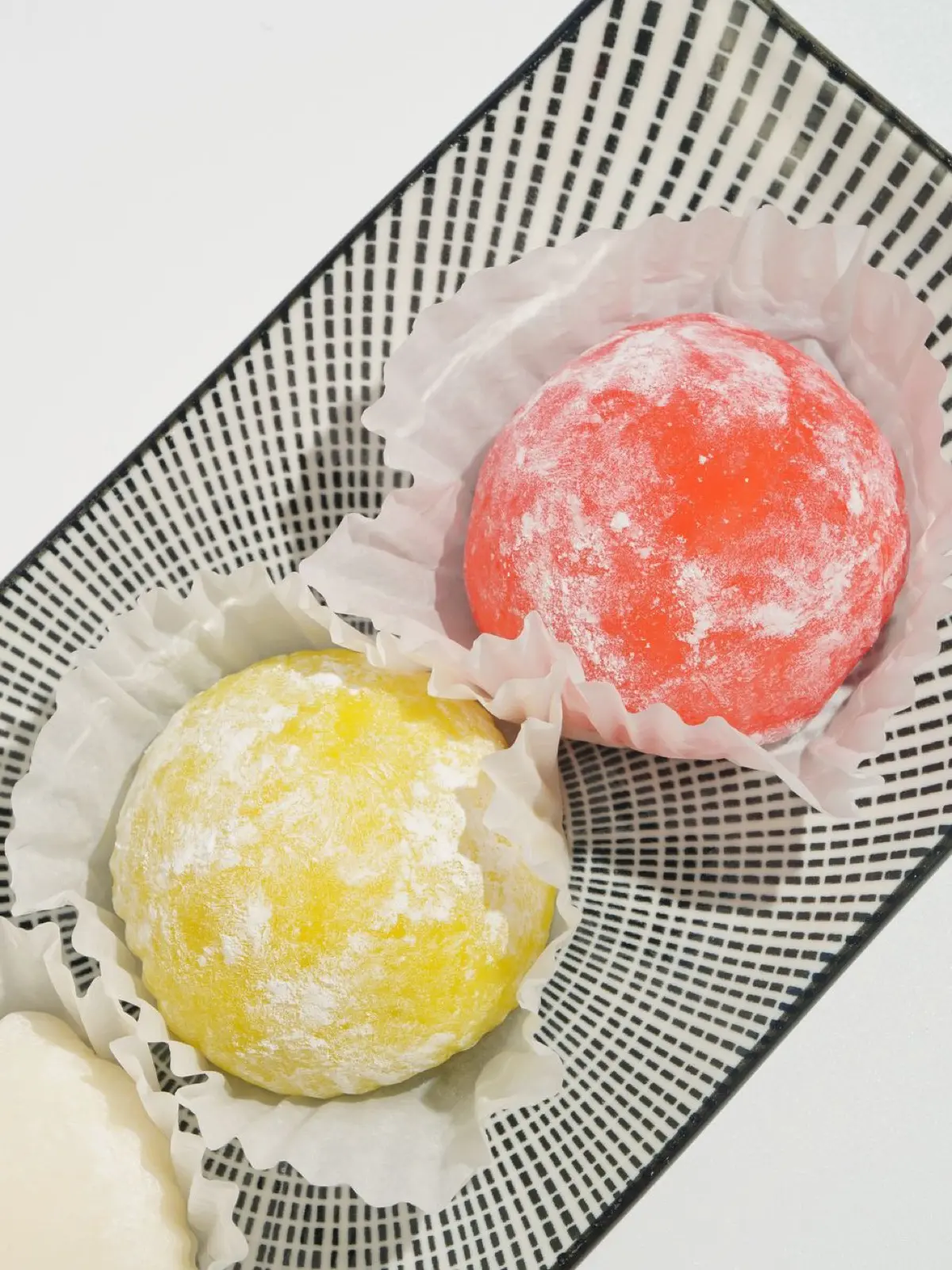 Round white mochi rice cakes stacked on red lacquer plates with pine decorations for Japanese New Year celebration.