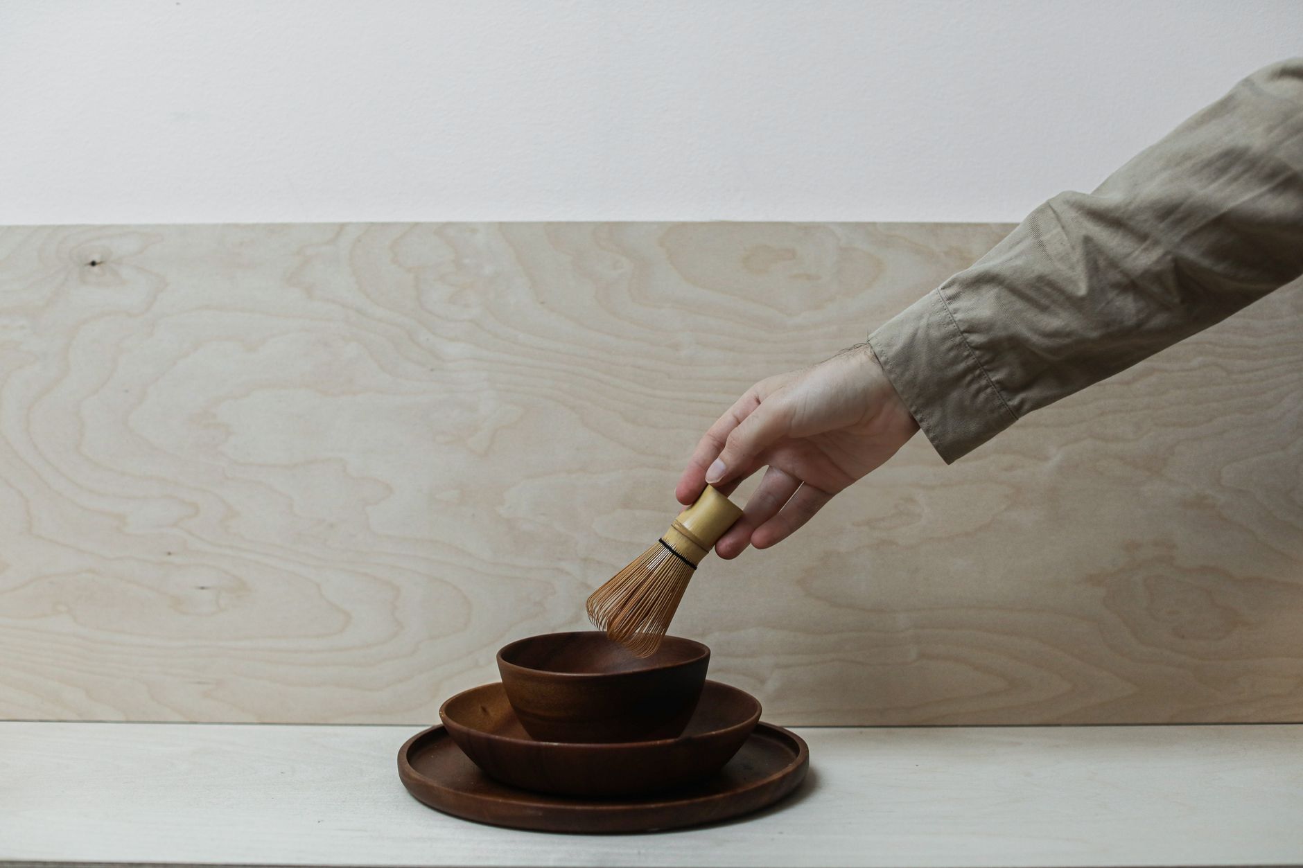 Vibrant green matcha powder whisked into foam inside a traditional ceramic tea bowl with bamboo chasen whisk nearby.