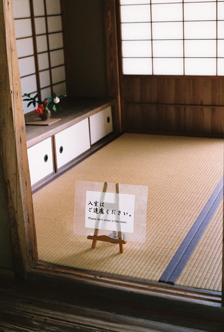 Traditional Japanese tatami room with woven rush mat flooring, sliding shoji screens, and low wooden table in minimalist interior.
