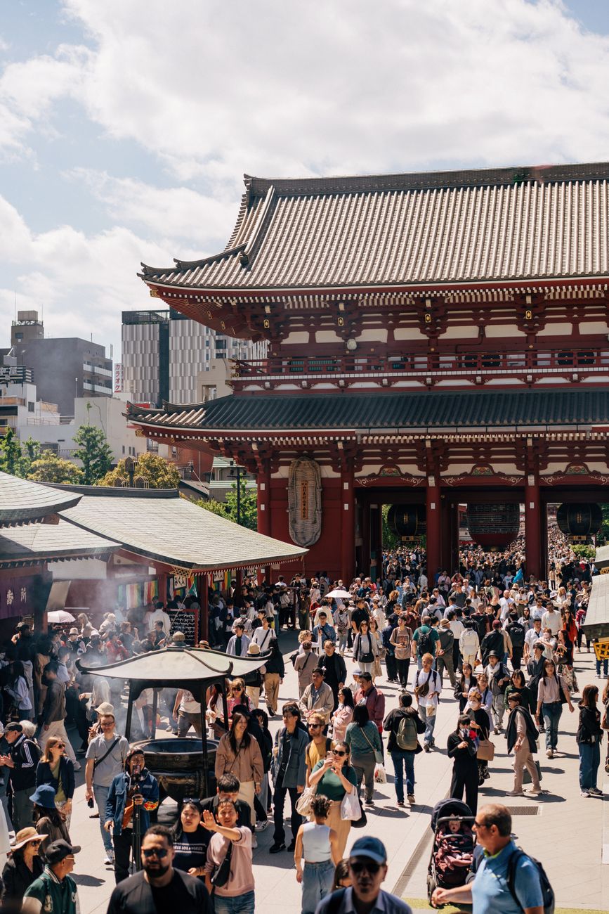 Festival participants in traditional happi coats carrying an ornate golden mikoshi shrine through crowded streets during a Japanese matsuri celebration.