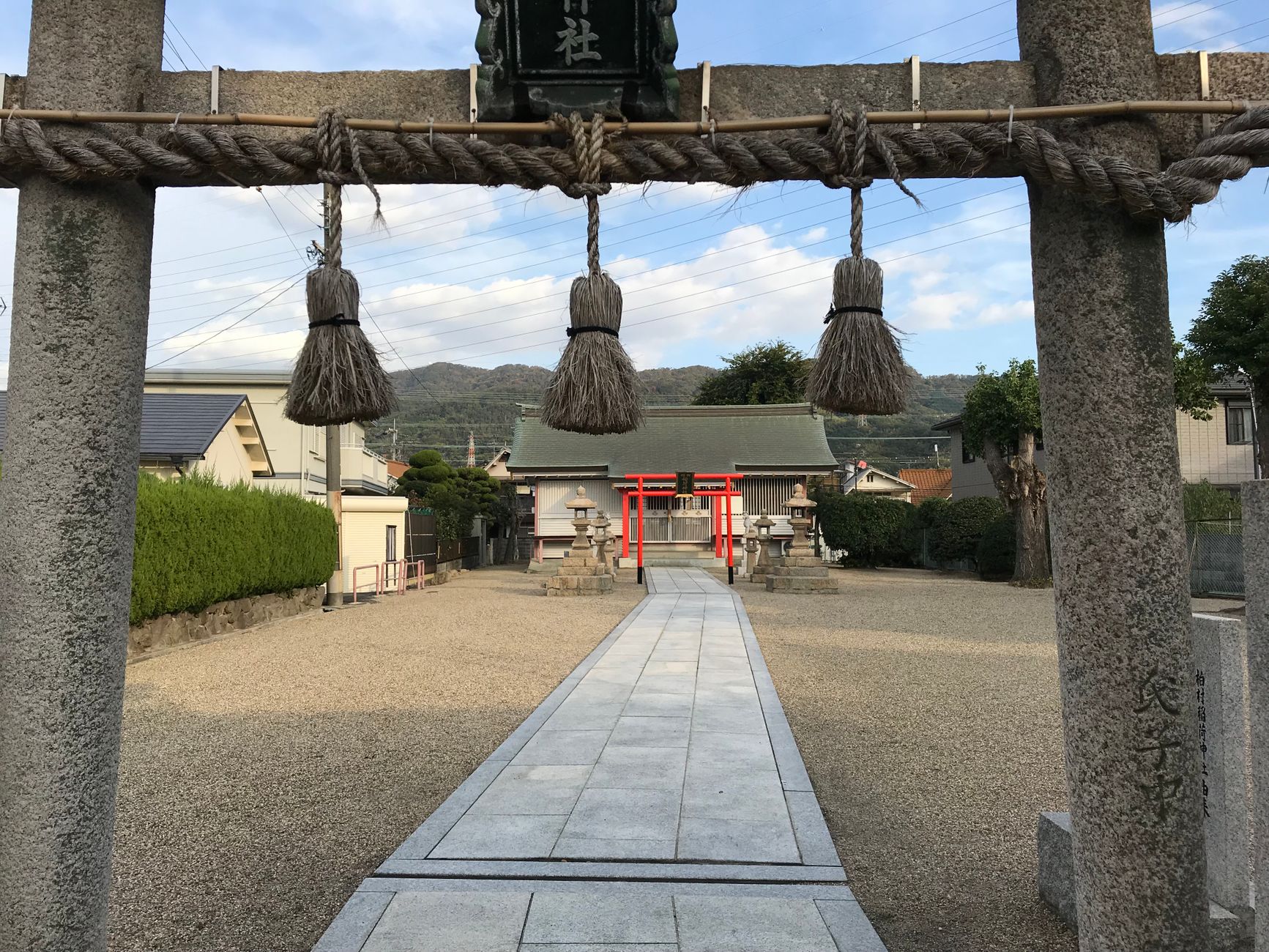 Thick twisted straw rope with white paper streamers hanging across the entrance of a traditional Japanese shrine gate.