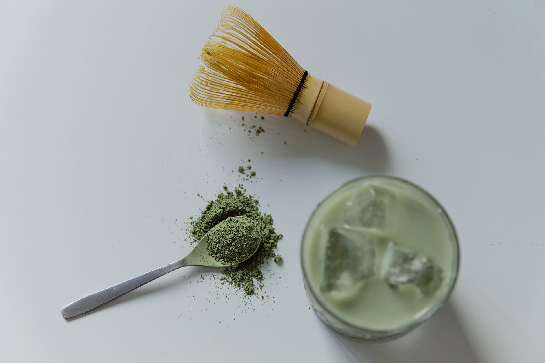 Traditional bamboo chasen whisk creating delicate foam on vibrant green matcha tea in a ceramic bowl