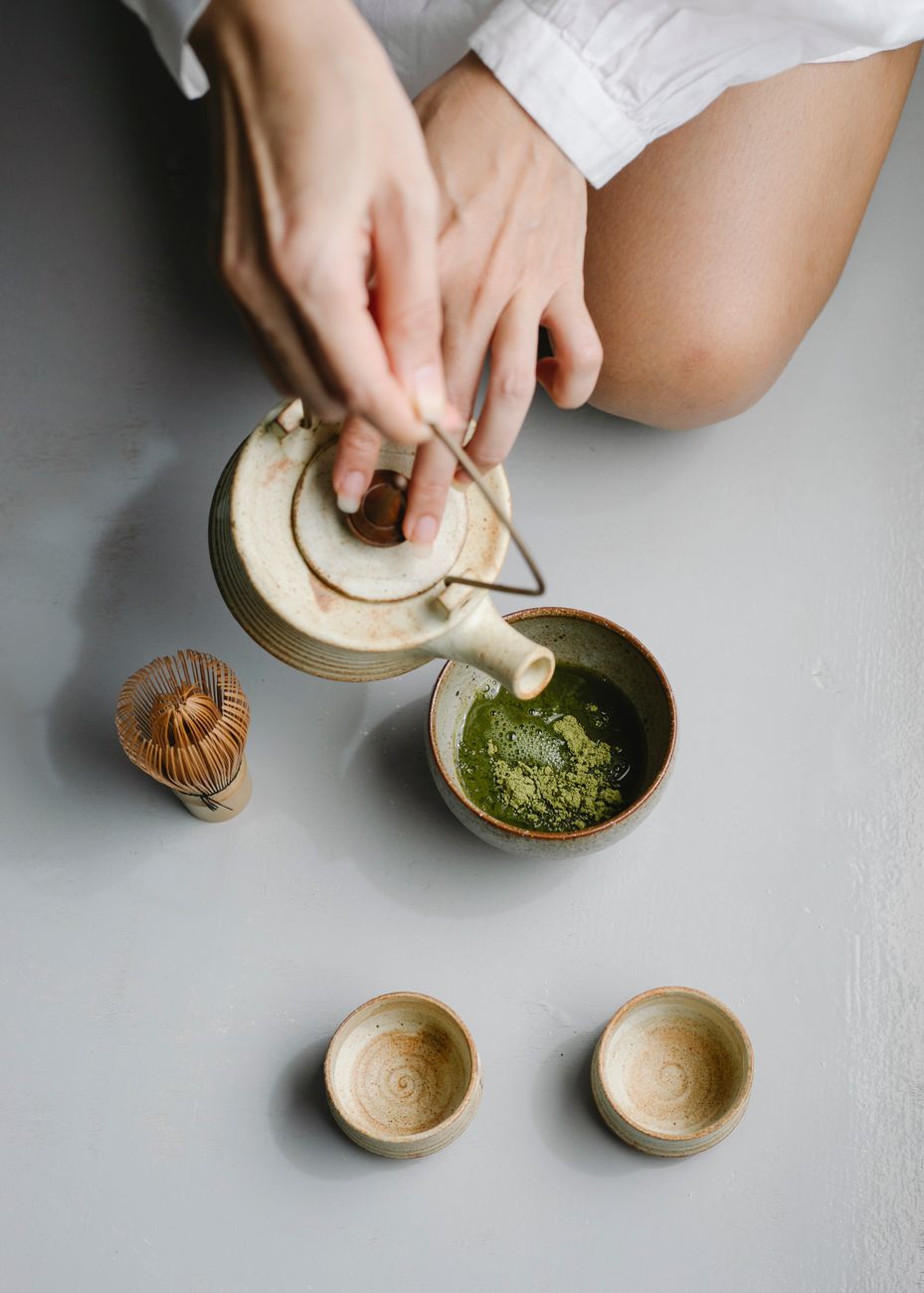 Traditional bamboo chasen whisk creating delicate foam on vibrant green matcha tea in a ceramic bowl