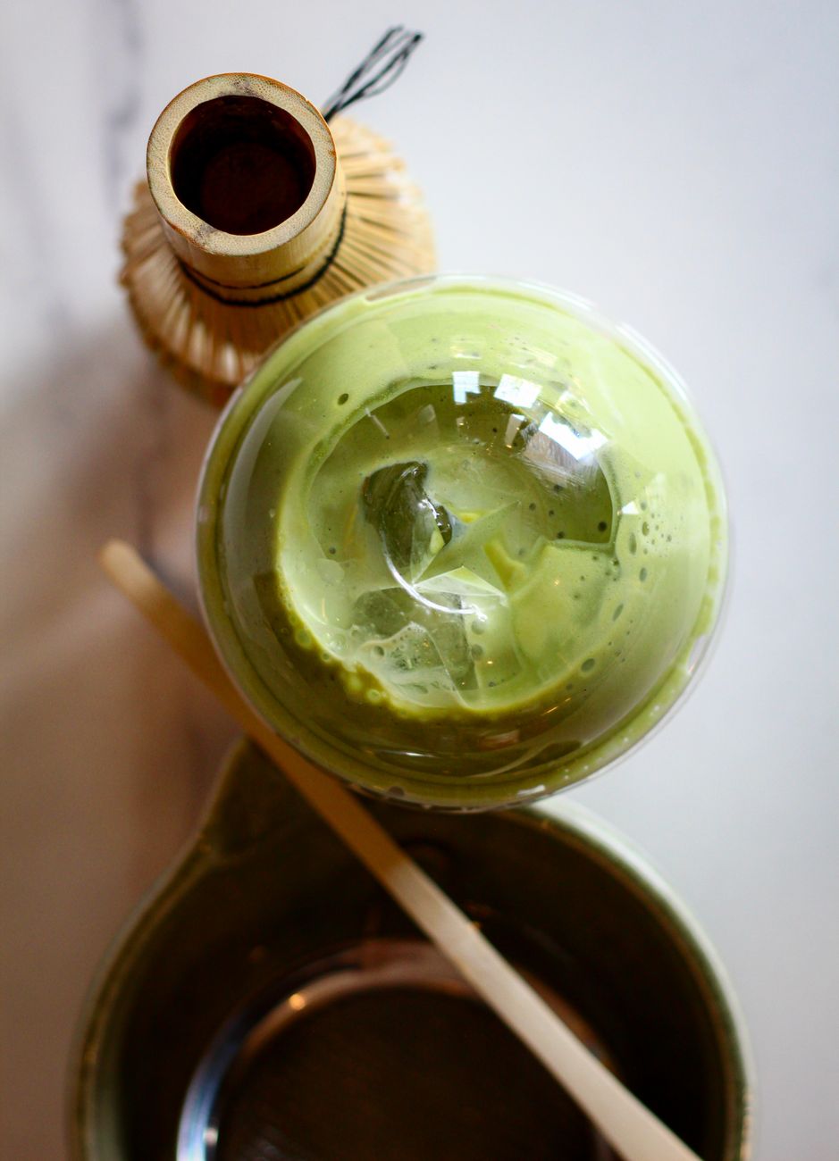 Hand-ground ceremonial matcha powder in vibrant jade green displayed beside bamboo whisk and traditional ceramic tea bowl.