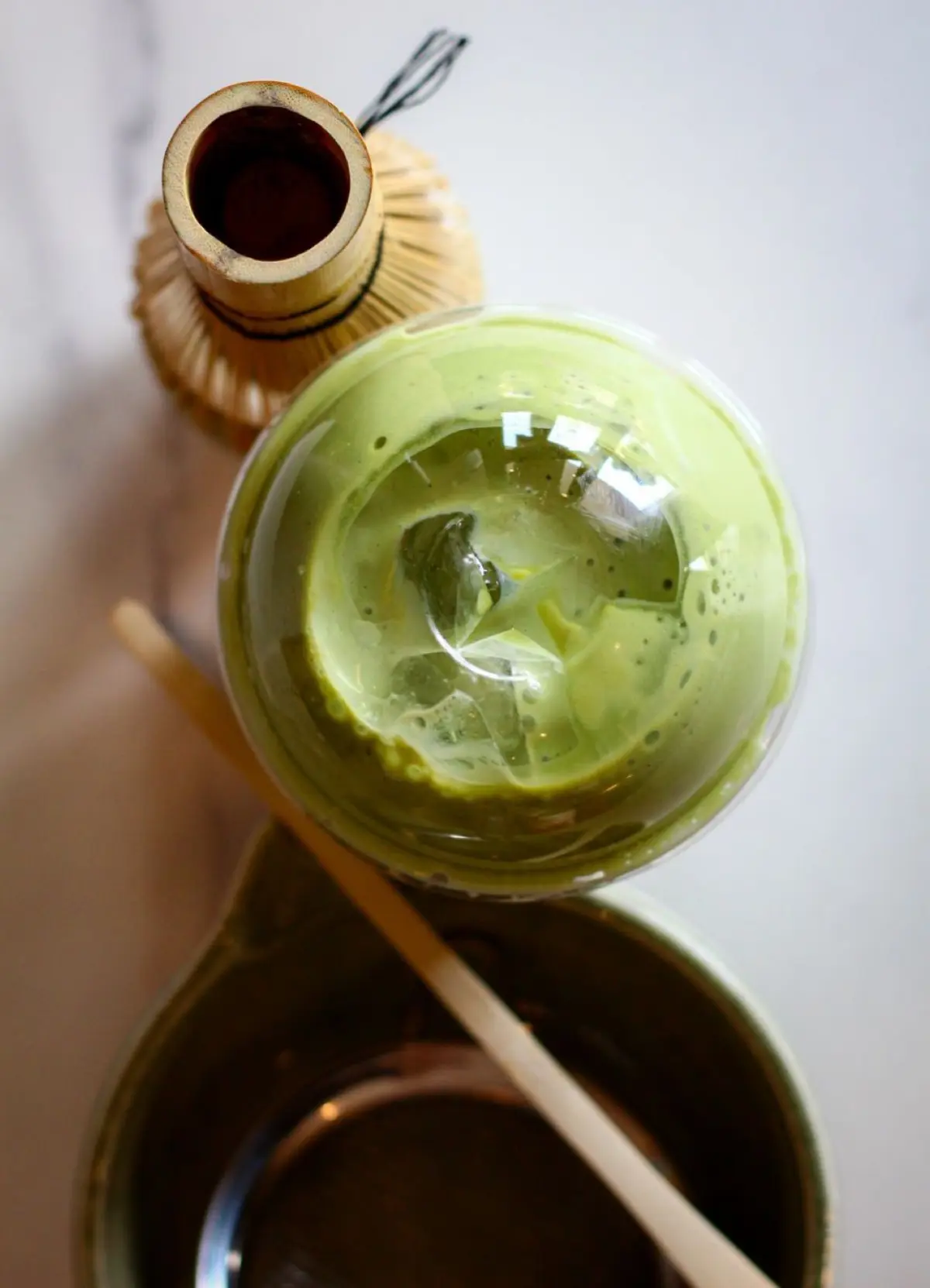 Hand-ground ceremonial matcha powder in vibrant jade green displayed beside bamboo whisk and traditional ceramic tea bowl.