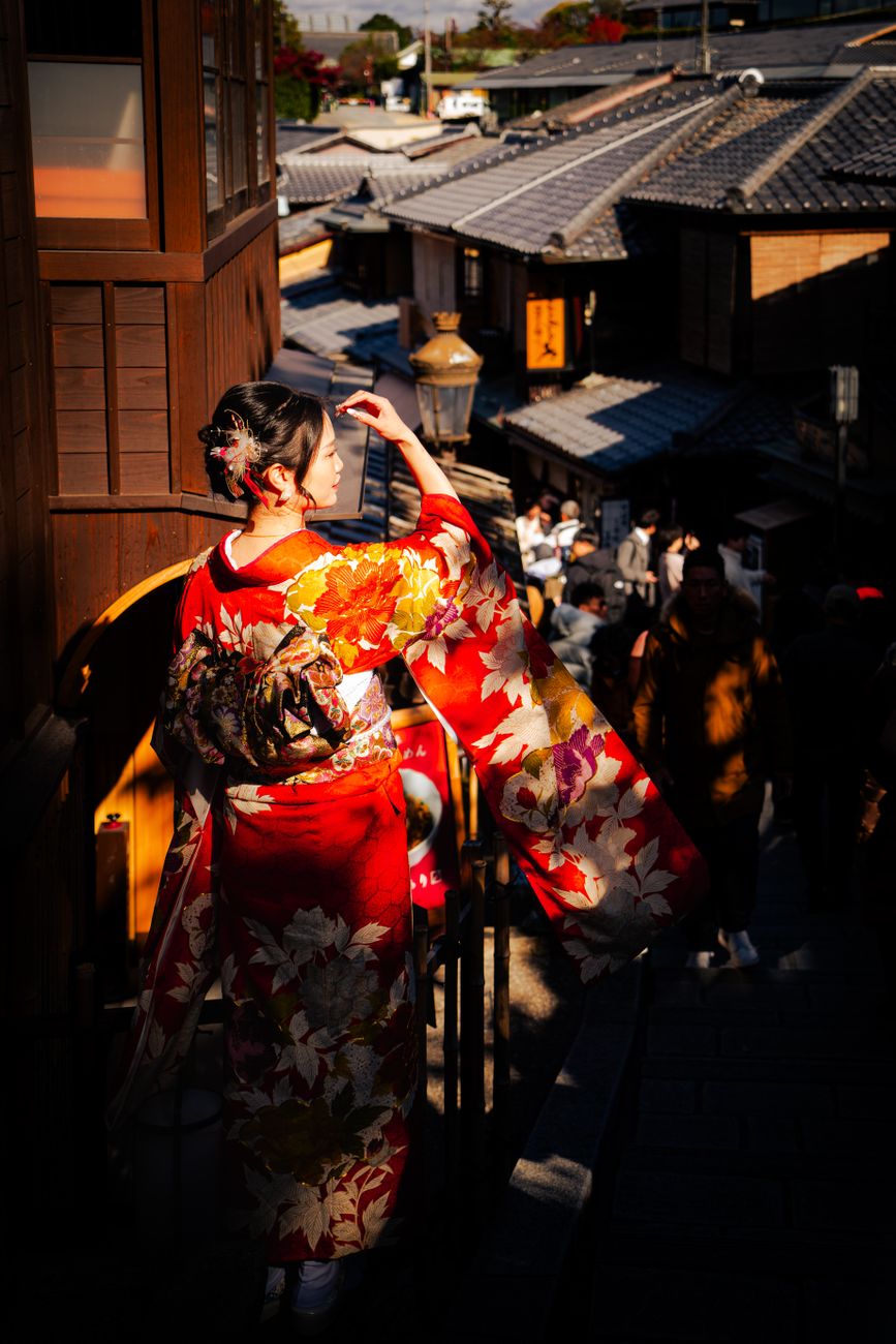 Traditional wooden machiya townhouses line a narrow stone-paved street in Gion at dusk with soft lantern light glowing.