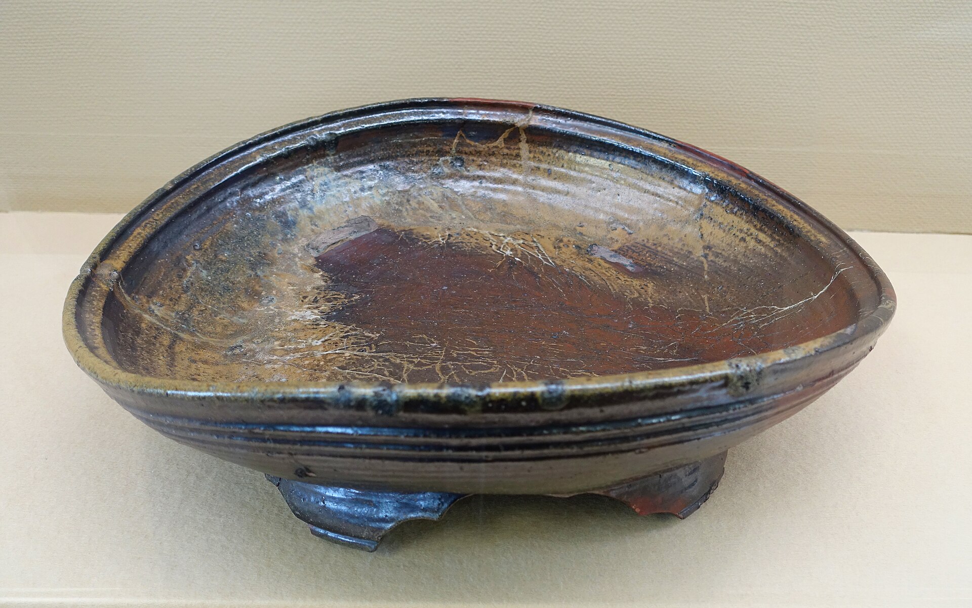 Traditional Bizen pottery vessels in earthy brown tones with natural ash glaze patterns from wood-firing, displayed on rustic wooden surface.