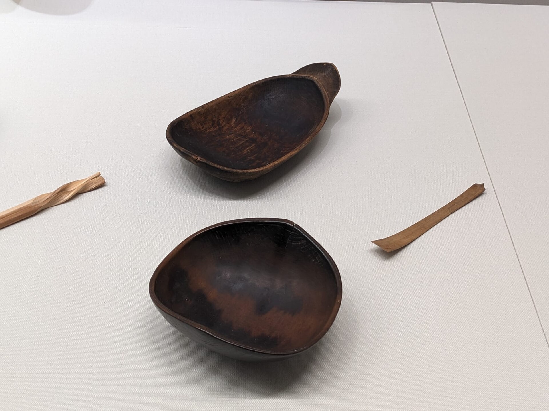 Artisan applying red urushi lacquer with a fine brush onto a wooden bowl in a traditional Wajima workshop.