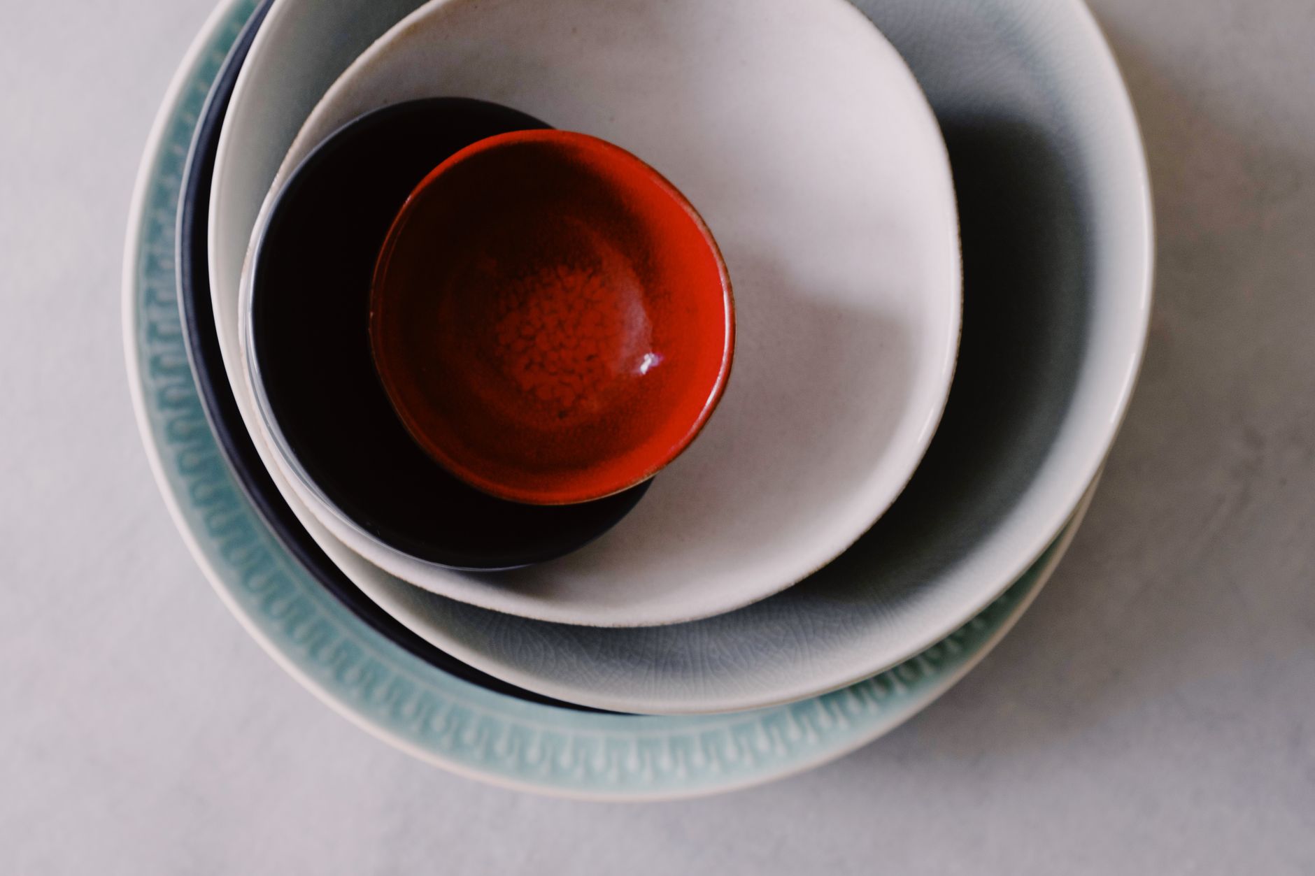 Artisan applying red urushi lacquer with a fine brush onto a traditional wooden bowl in an Aizu workshop.