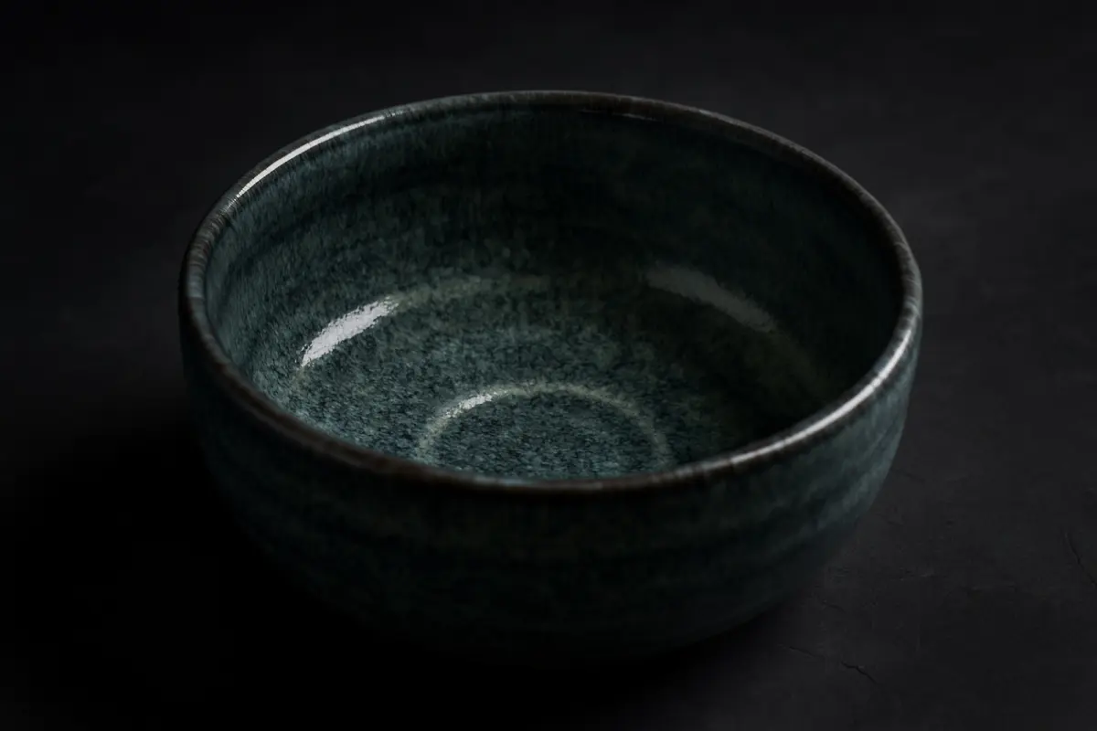 Traditional Mino ware ceramic bowls displaying various glazing techniques including Shino, Oribe, and Seto-guro styles arranged on wooden surface.