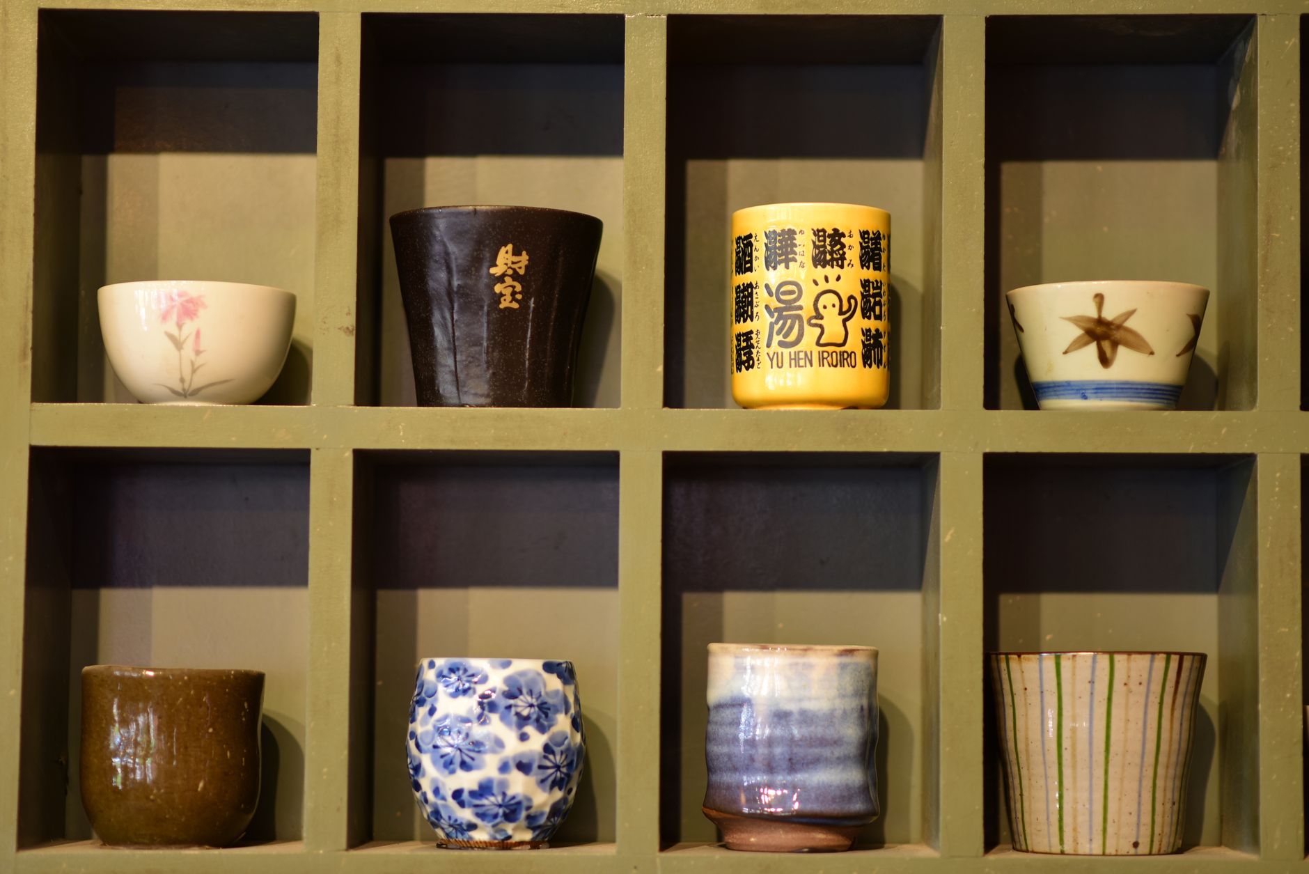 Stack of simple white Hasami ware plates and bowls arranged on a wooden table in a Japanese home kitchen.