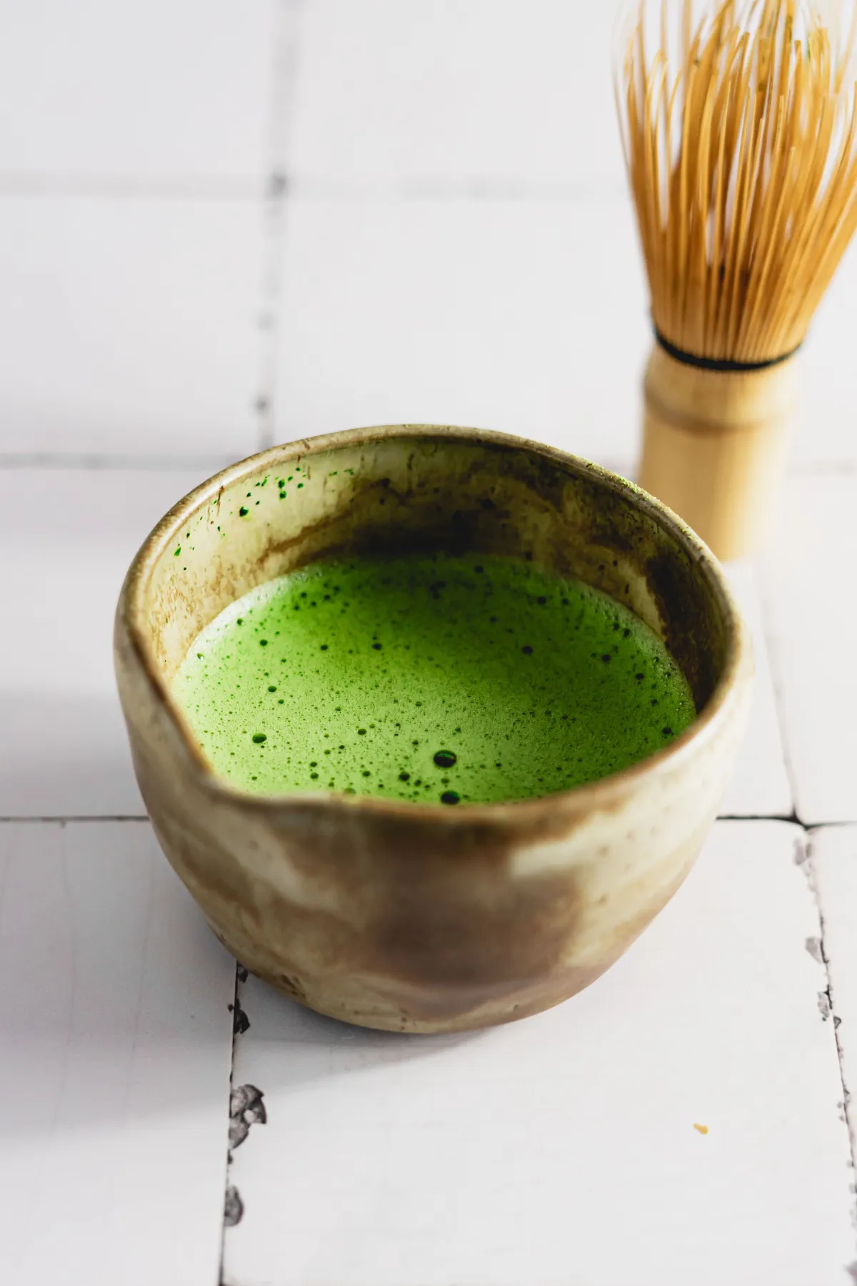 Raku-fired tea bowl with irregular glaze drips, asymmetrical rim, and natural clay texture showing wabi-sabi principles.