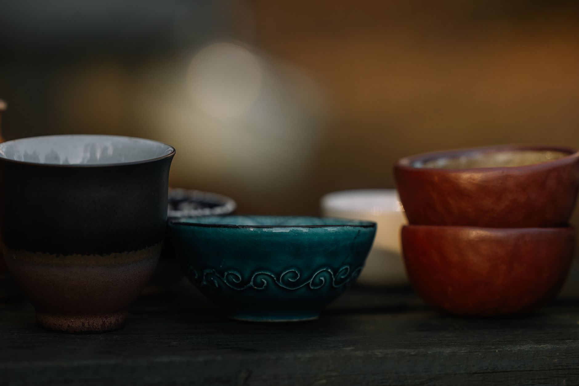 Close-up of tenmoku glazed tea bowl showing iridescent oil-spot pattern and iron-rich black surface with brown rim.