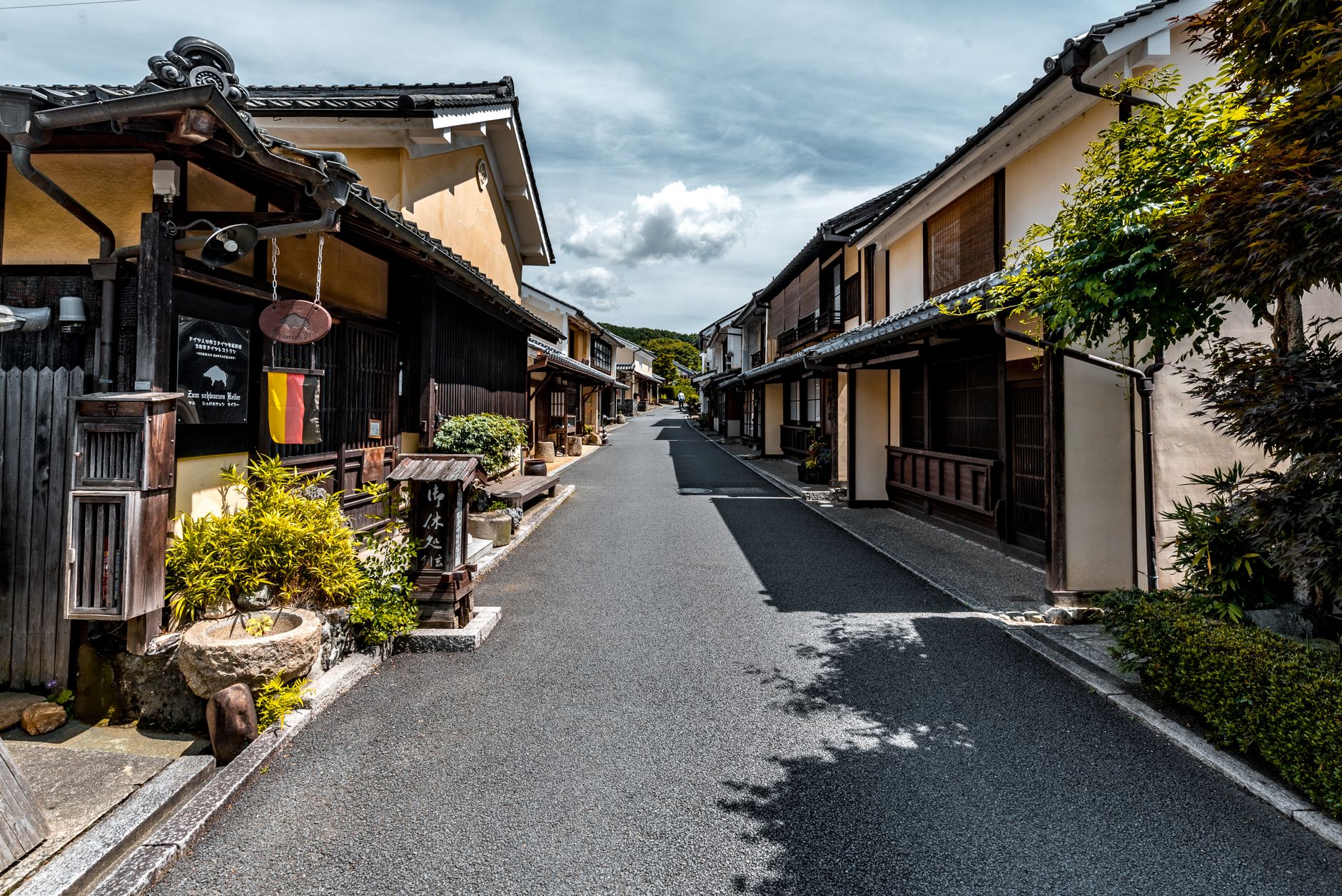 Traditional Japanese pottery workshop with wooden shelves displaying ceramic bowls and plates in an historic kiln town alleyway.