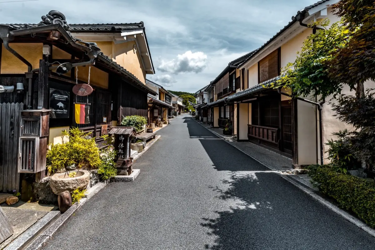 Traditional Japanese pottery workshop with wooden shelves displaying ceramic bowls and plates in an historic kiln town alleyway.