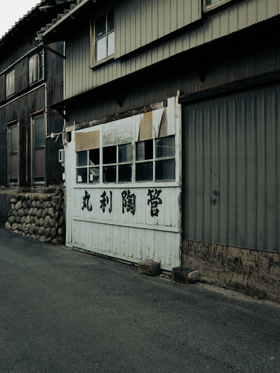 Traditional Japanese pottery workshop with wooden shelves displaying ceramic bowls and plates in an historic kiln town alleyway.