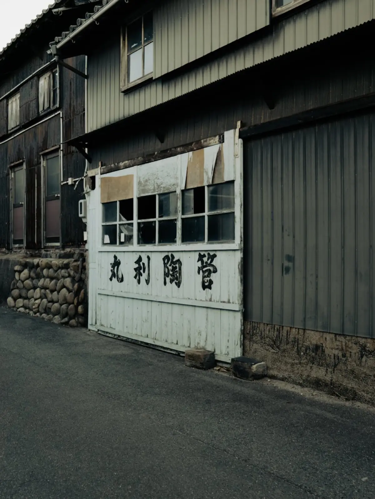 Traditional Japanese pottery workshop with wooden shelves displaying ceramic bowls and plates in an historic kiln town alleyway.