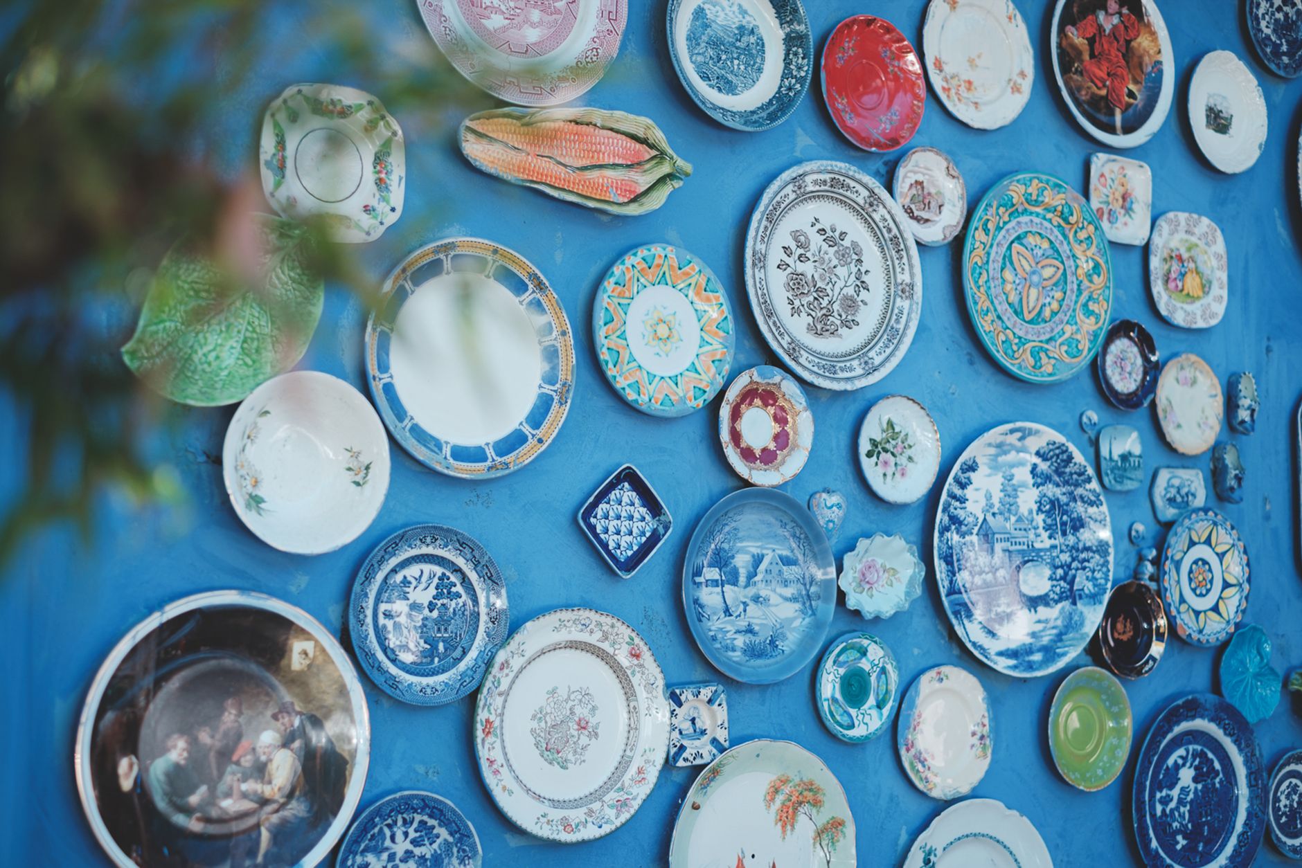 Artisan painting delicate floral motifs with cobalt pigment onto bisque-fired porcelain bowl using fine brush technique.