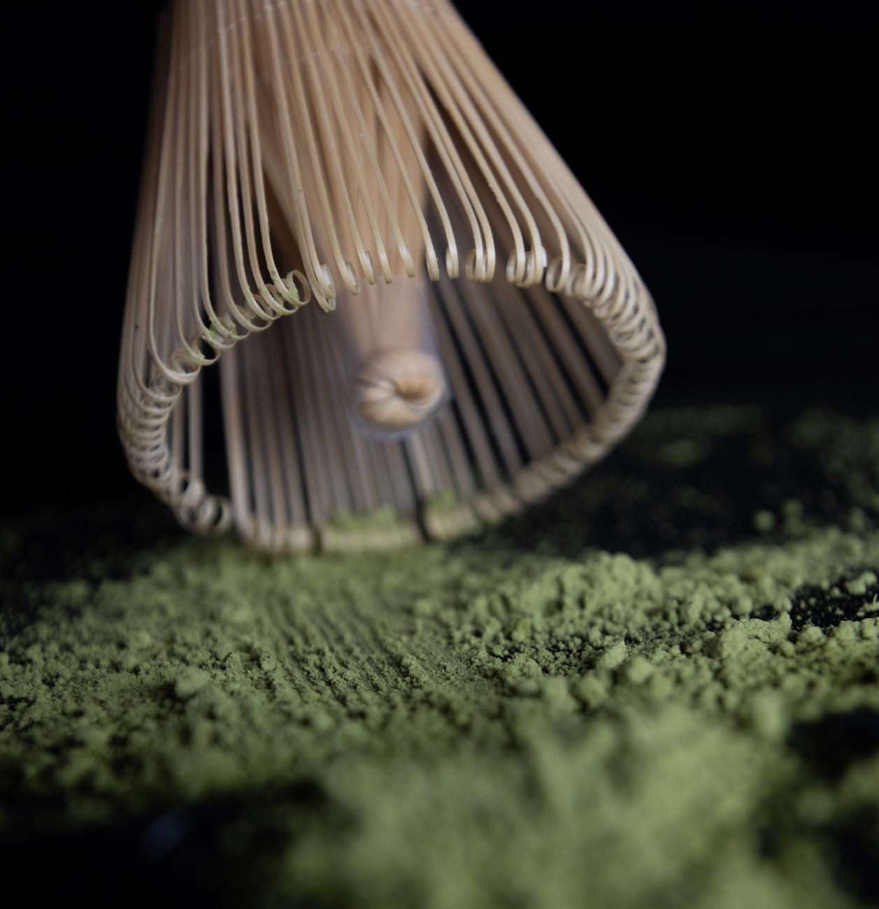 Traditional stone mill grinding vibrant green matcha powder from tencha leaves in a Japanese tea preparation setting.