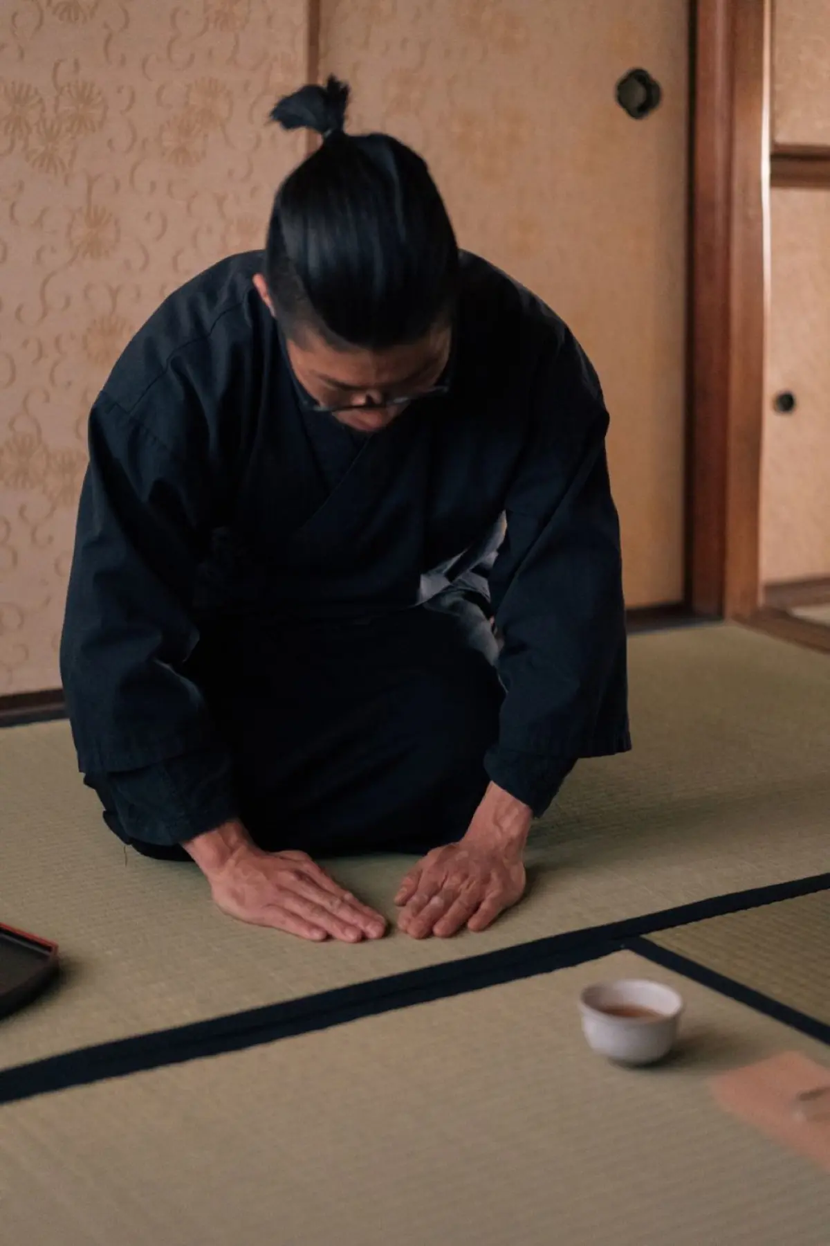 Toasted brown rice grains mixed with green tea leaves in a traditional ceramic bowl on wooden surface.