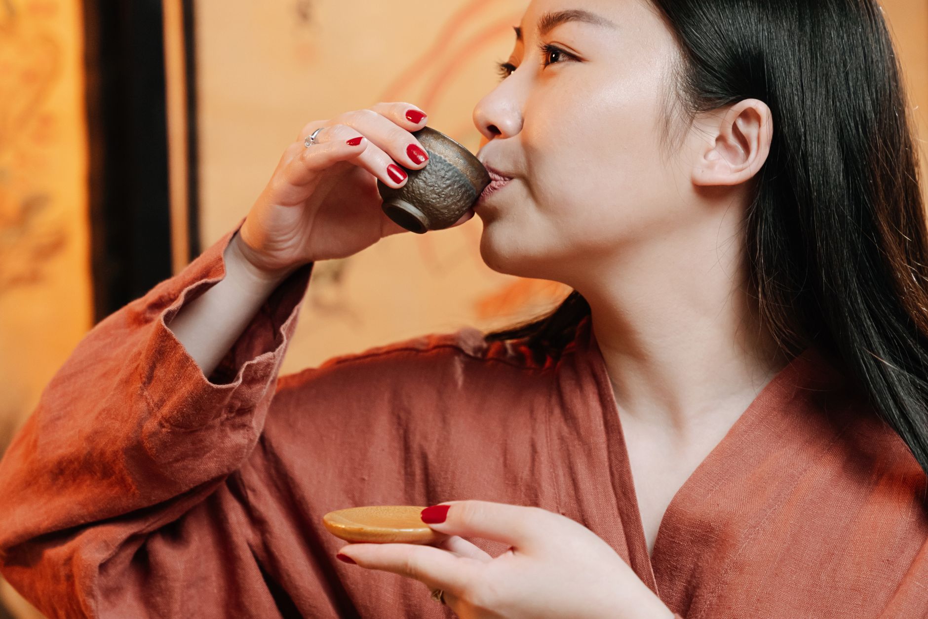 Green bancha tea leaves steeping in a traditional Japanese ceramic teapot with a filled cup beside it on wooden table.