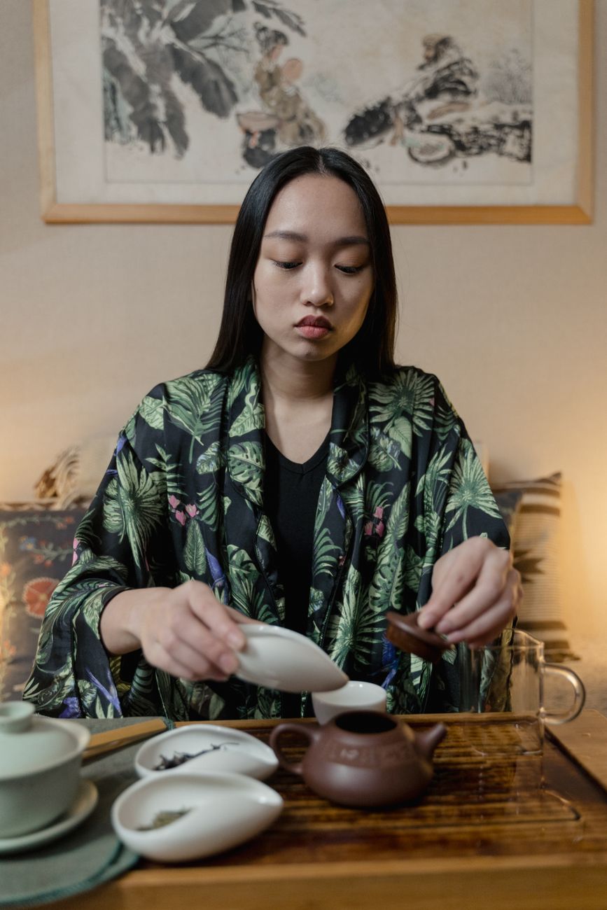 Fresh green shincha tea leaves being hand-picked from a Japanese tea field in early spring morning light.