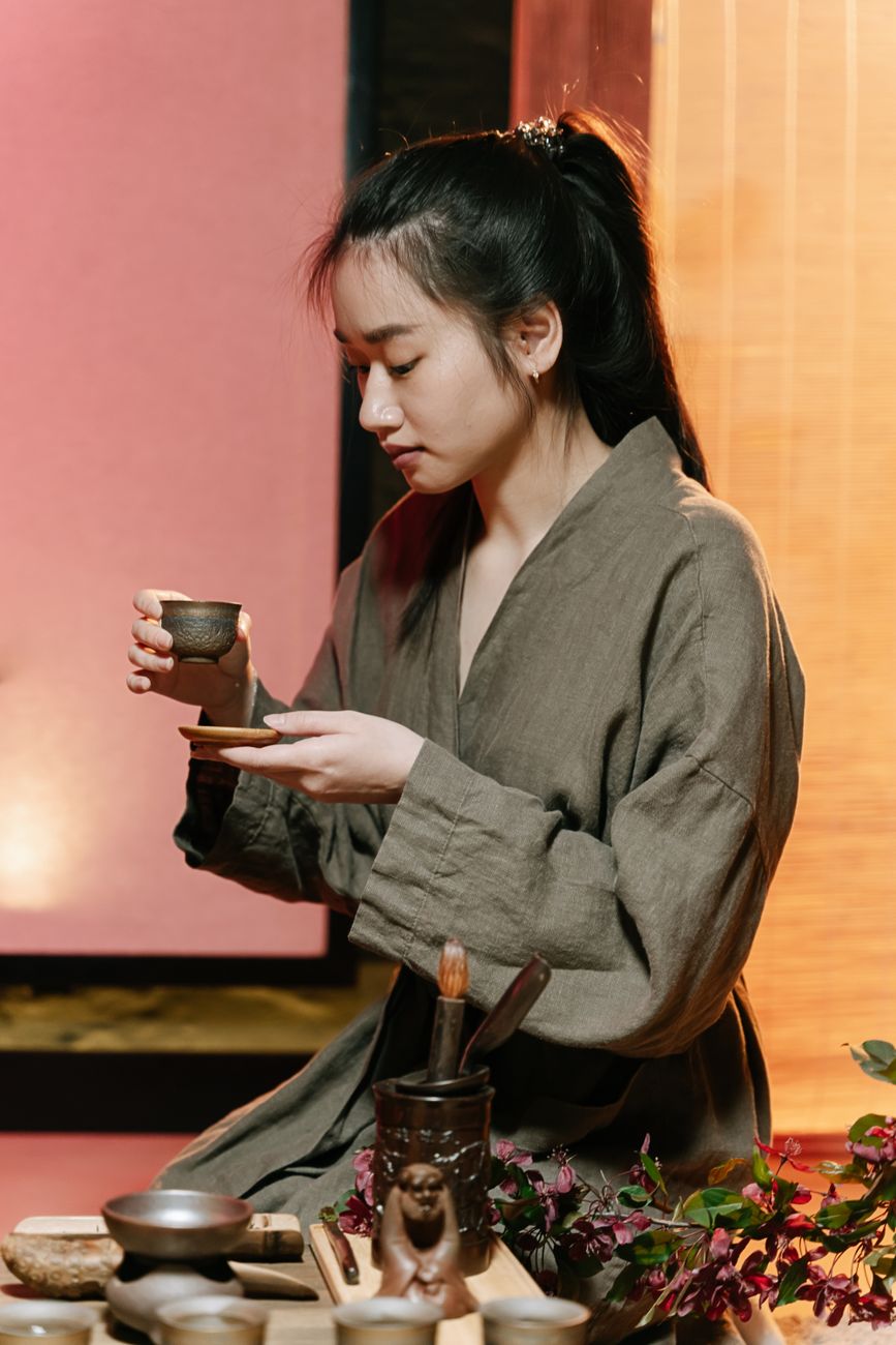 Traditional Japanese tea ceremony practitioner in kimono whisking matcha in a ceramic bowl within a minimalist tatami room.