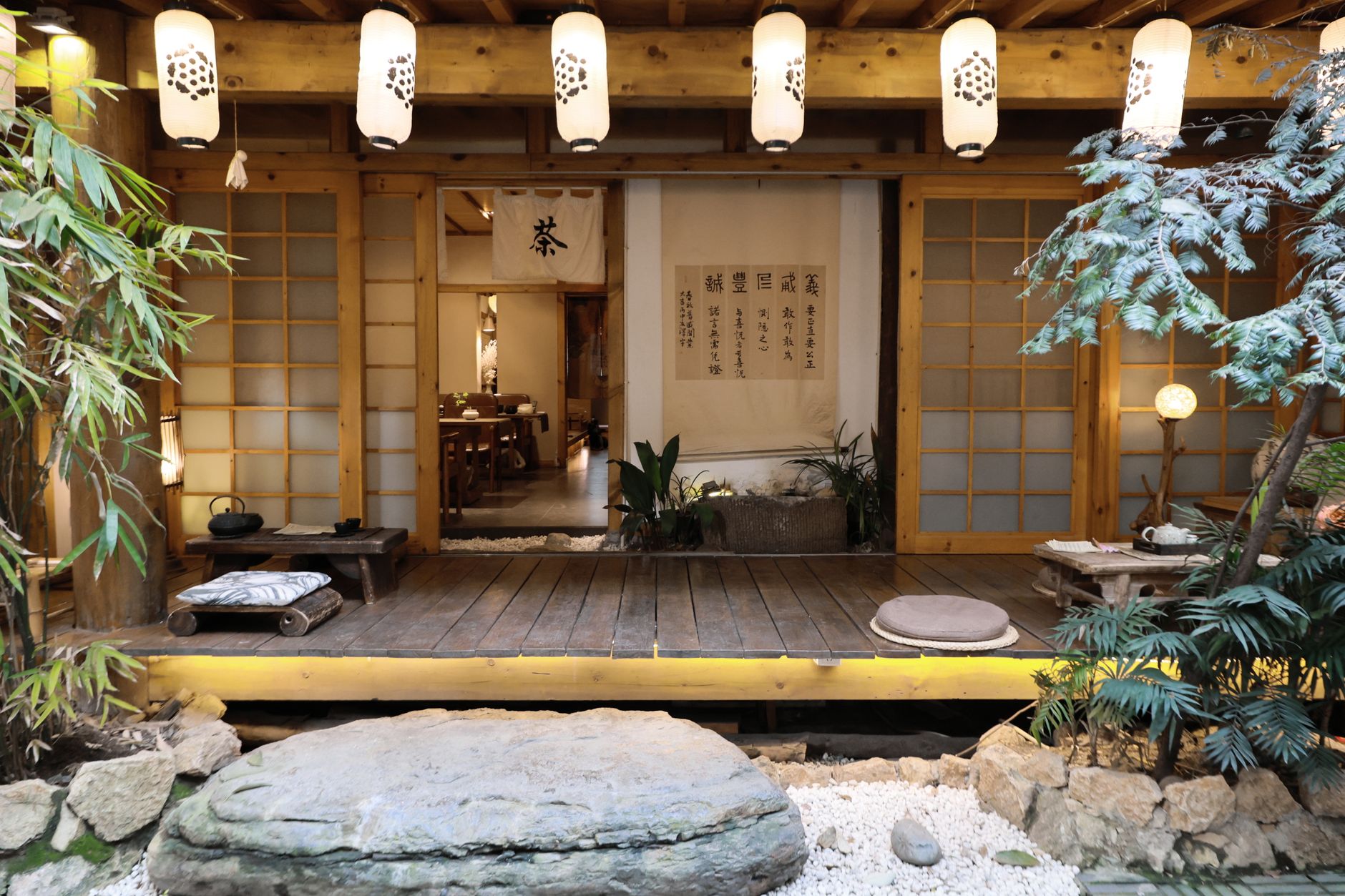 Traditional Japanese tea ceremony scene showing a host in kimono whisking matcha in a ceramic bowl on tatami mats.