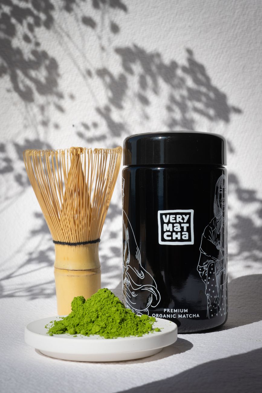 Traditional Japanese tea ceremony host preparing matcha in a minimalist tea room with tatami mats and simple bamboo utensils.