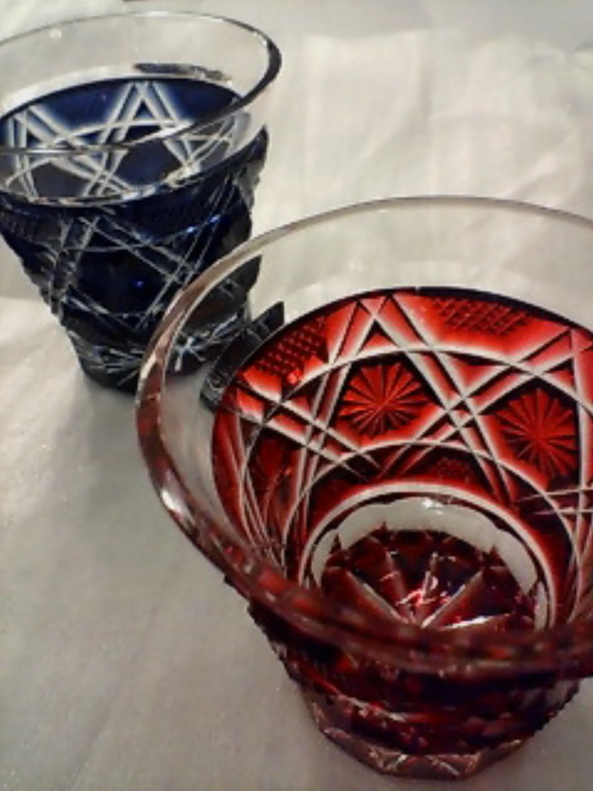 Traditional Satsuma Kiriko cut glass vessel displaying vibrant ruby red overlay with intricate geometric patterns in brilliant faceted cuts.