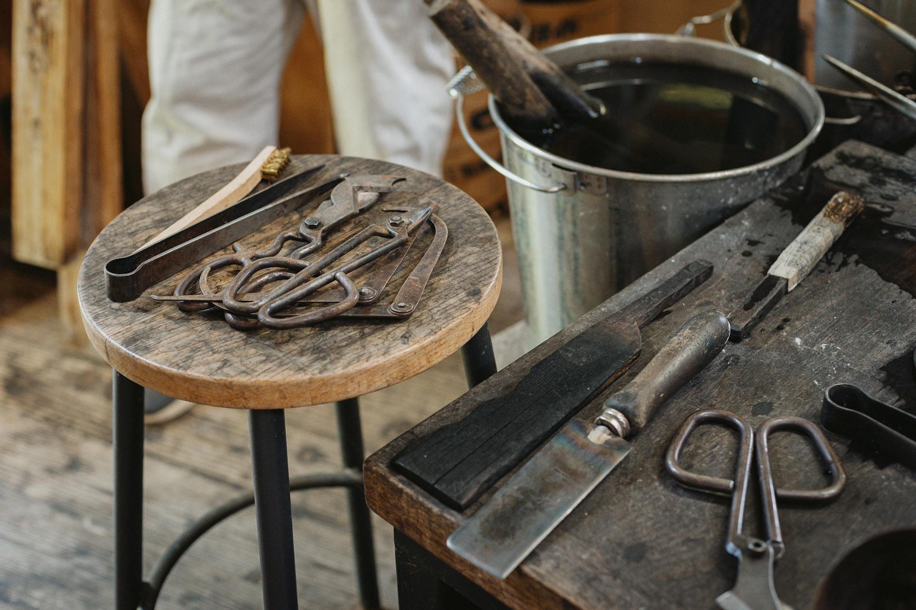 Artisan heating molten glass over flame to shape a delicate blue drinking vessel in traditional Japanese workshop.