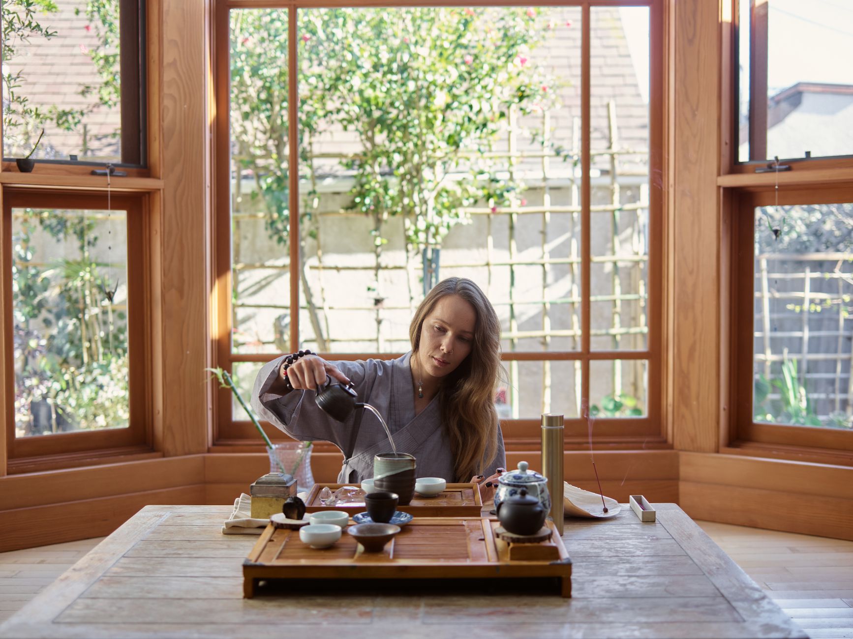 Tea master carefully arranging flowers and scrolls in a traditional tearoom alcove for a once-in-a-lifetime gathering.