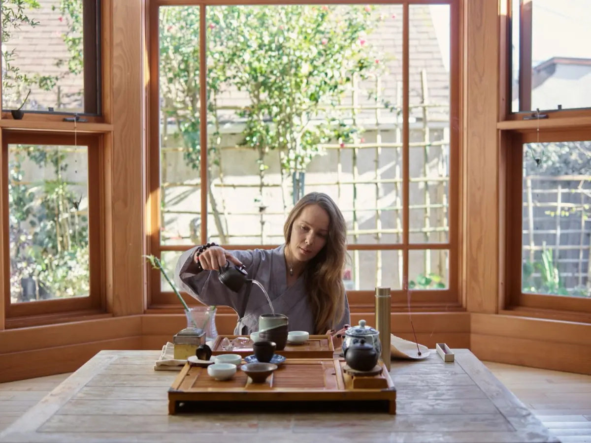 Tea master carefully arranging flowers and scrolls in a traditional tearoom alcove for a once-in-a-lifetime gathering.