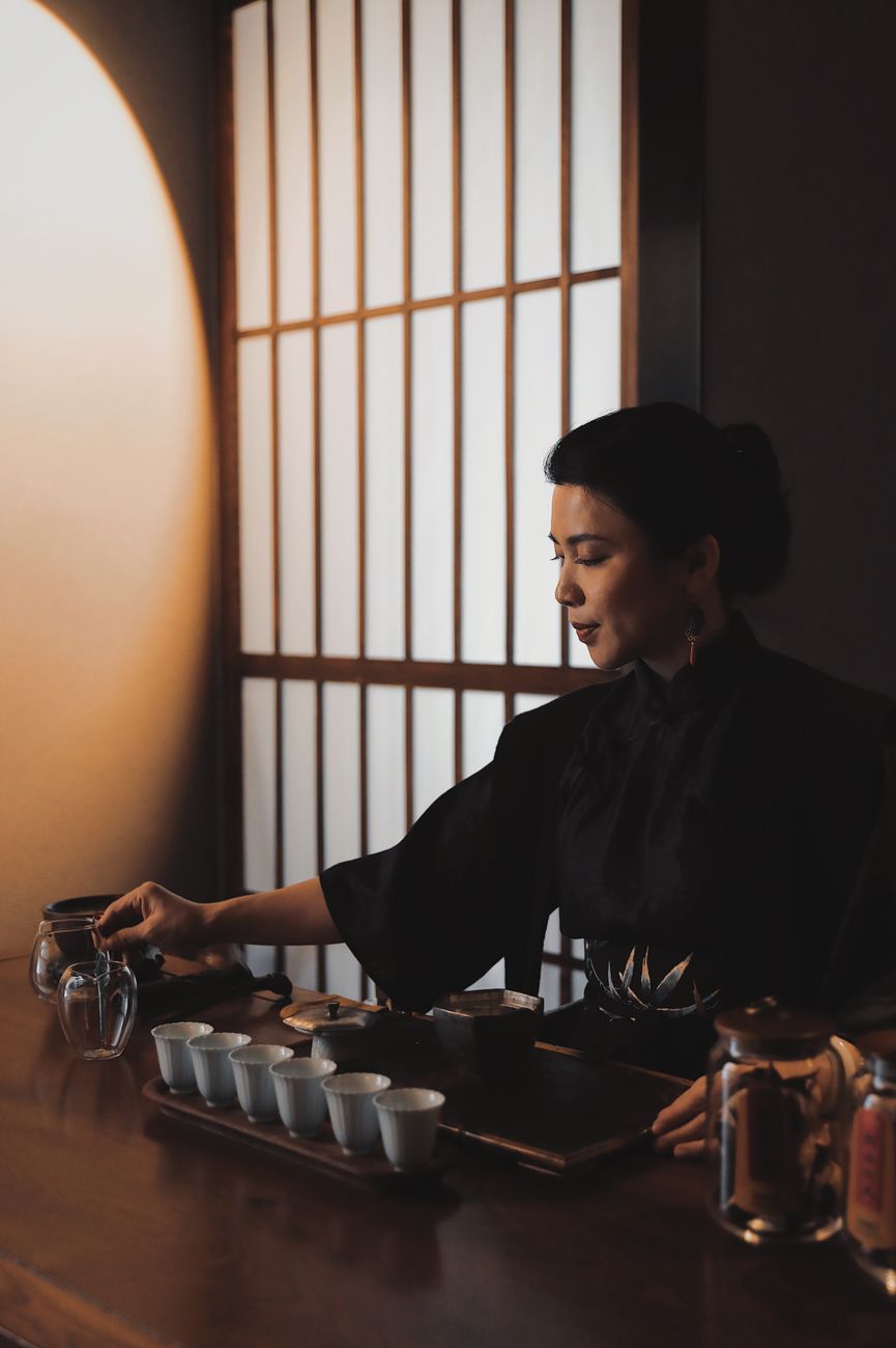 Tea master carefully arranging flowers and scrolls in a traditional tearoom alcove for a once-in-a-lifetime gathering.