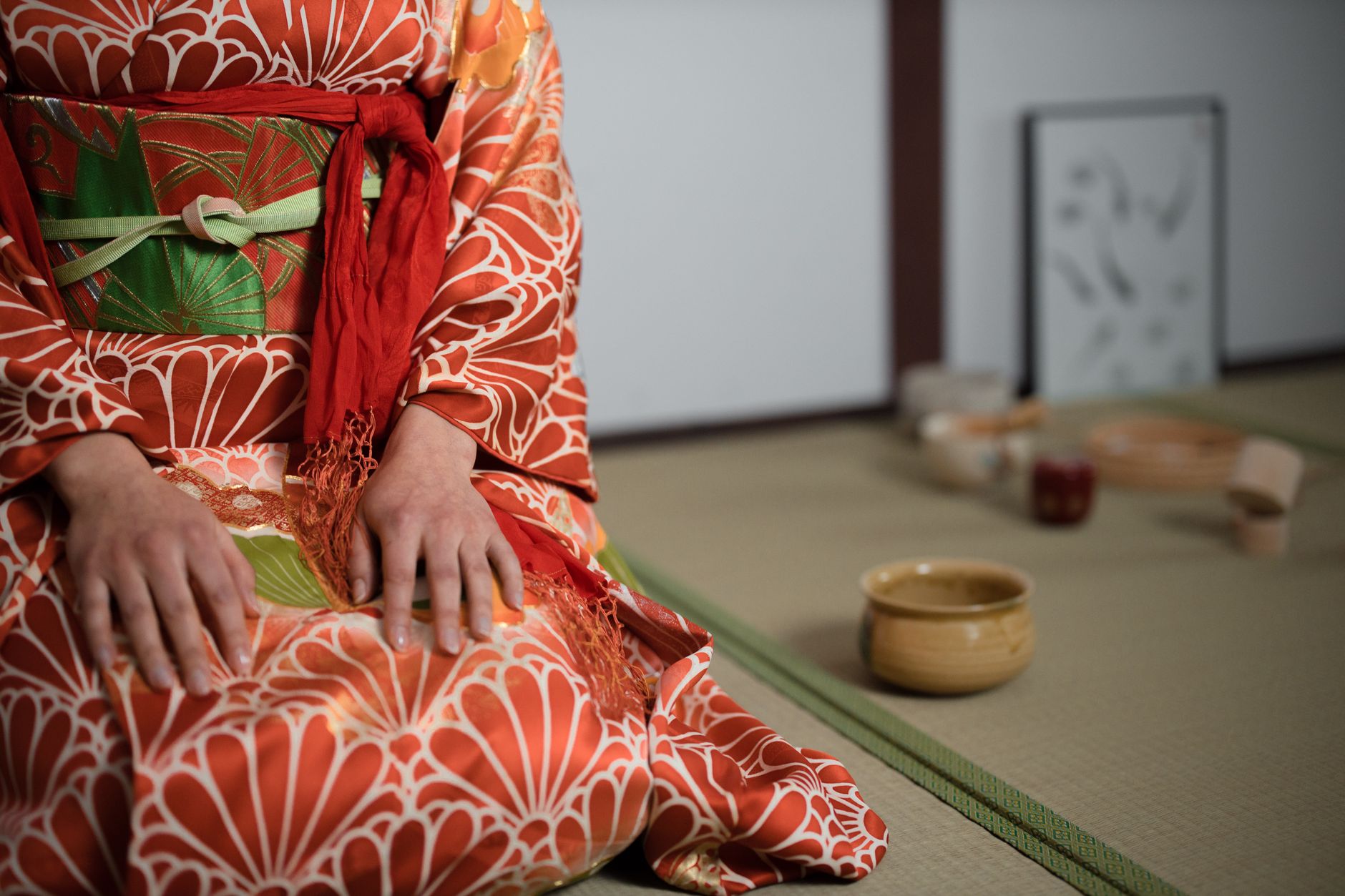Traditional Japanese chashitsu interior showing tatami flooring, shoji paper screens, tokonoma alcove, and simple wooden tea utensils arrangement.