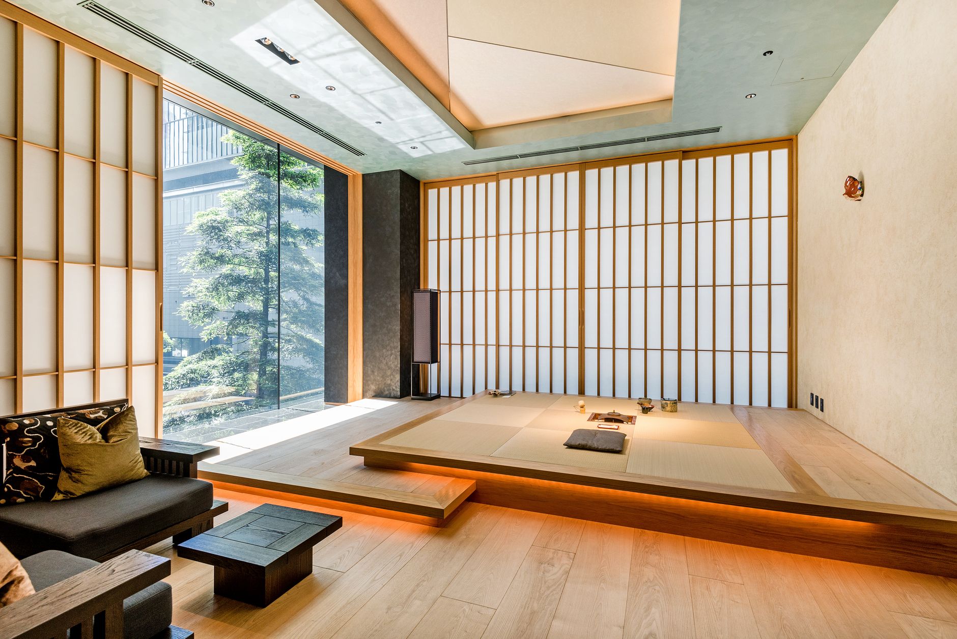Traditional Japanese tokonoma alcove in a tea room featuring a hanging scroll, ikebana flower arrangement, and tatami mat flooring.