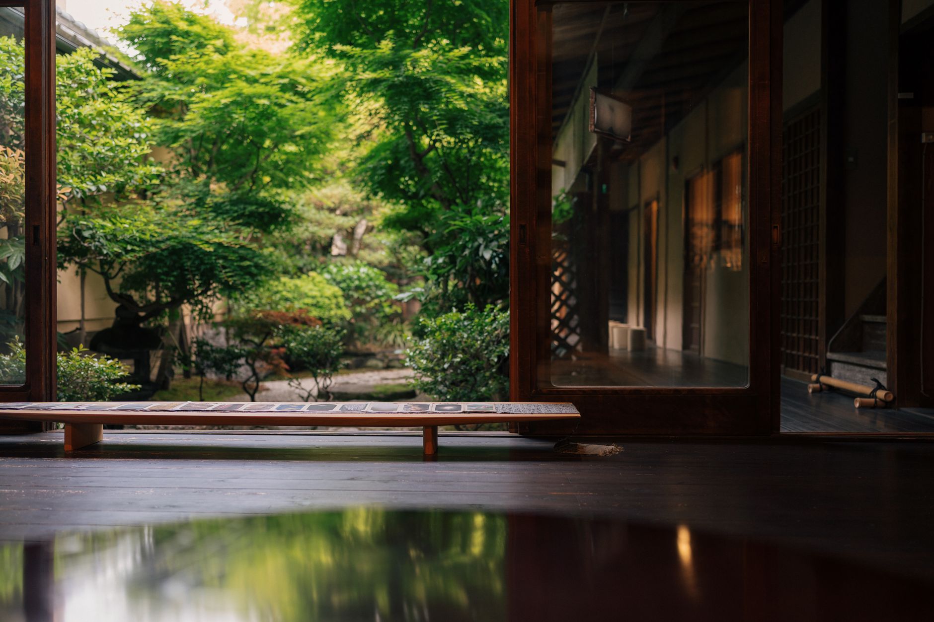 Buddhist monks preparing matcha tea in a traditional Japanese temple garden surrounded by carefully pruned tea plants and stone lanterns.